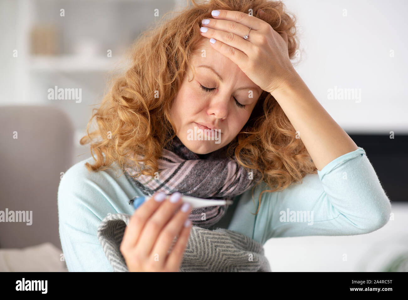 Woman feeling terrible while touching her forehead and having fever Stock Photo