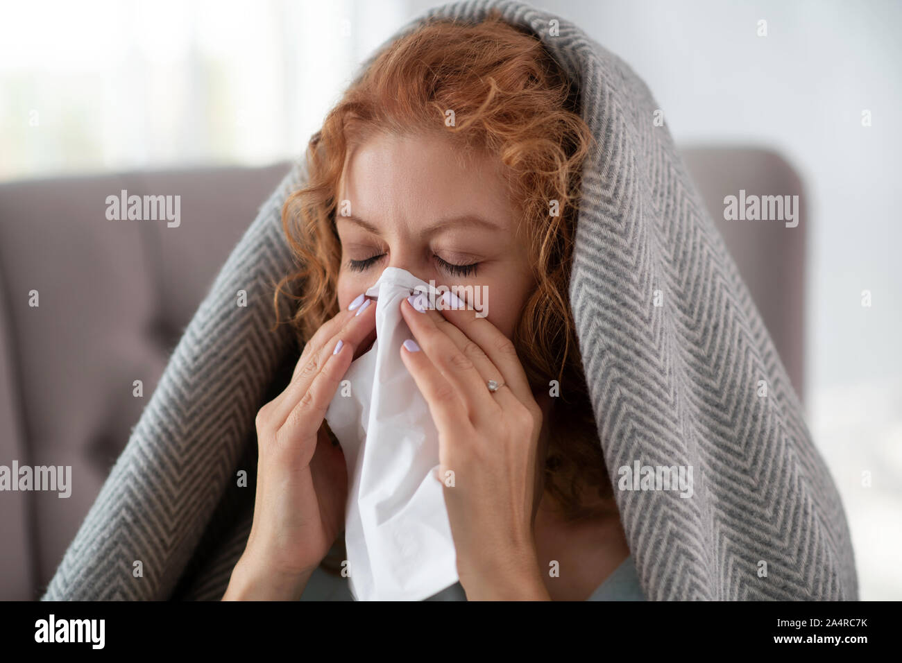 Woman closing eyes while sneezing and having running nose Stock Photo