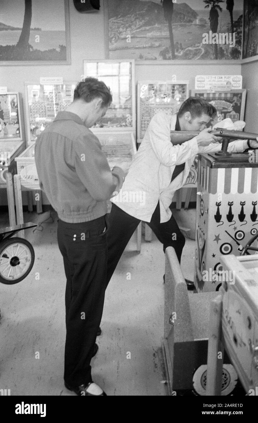 Elvis Presley in an arcade with Gene Smith. The precise location is uncertain, but the arcade was in Detroit, Michigan, and Elvis was relaxing in between shows at the Fox Theater on May 25, 1956. The arcade was likely very close to the theater. Stock Photo