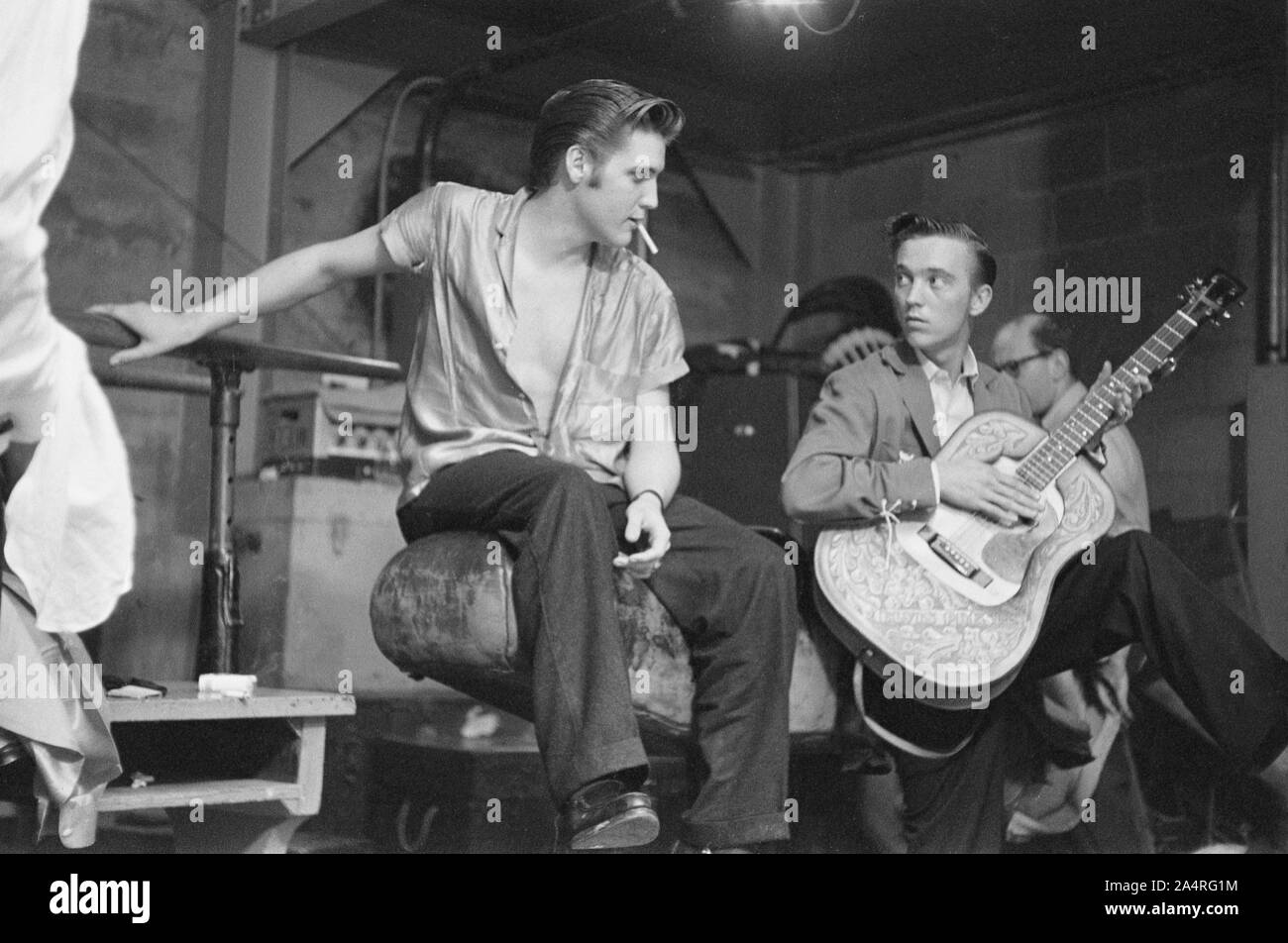 Elvis Presley, Scotty Moore, and Gene Smith backstage at the University of Dayton Fieldhouse, May 27, 1956. Photographer Marvin Israel is partially visible in the background. Stock Photo