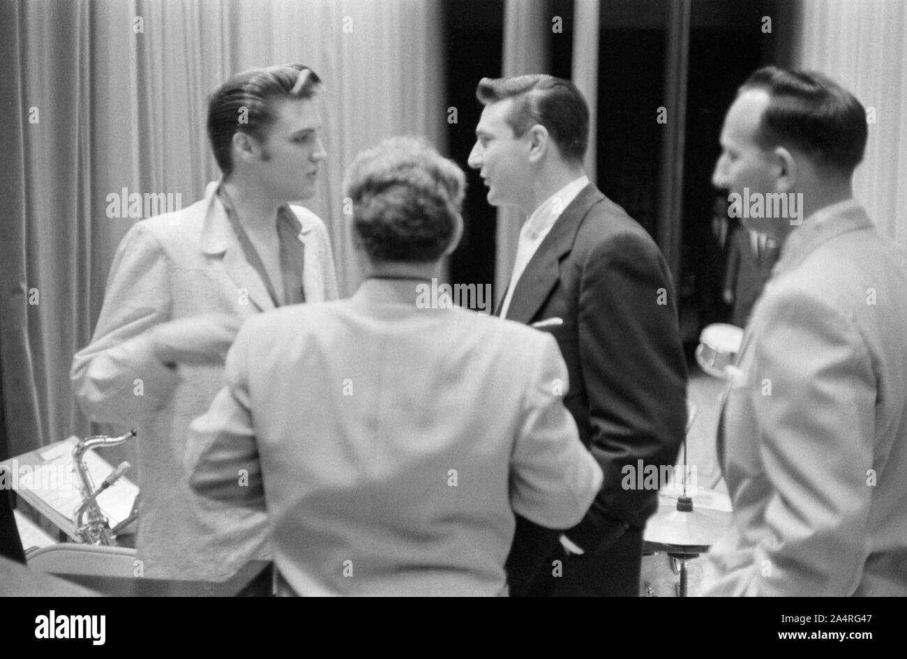 Elvis Presley speaking with several men, probably music industry executives, while waiting for a show to start at the University of Dayton Fieldhouse, May 27, 1956. Stock Photo