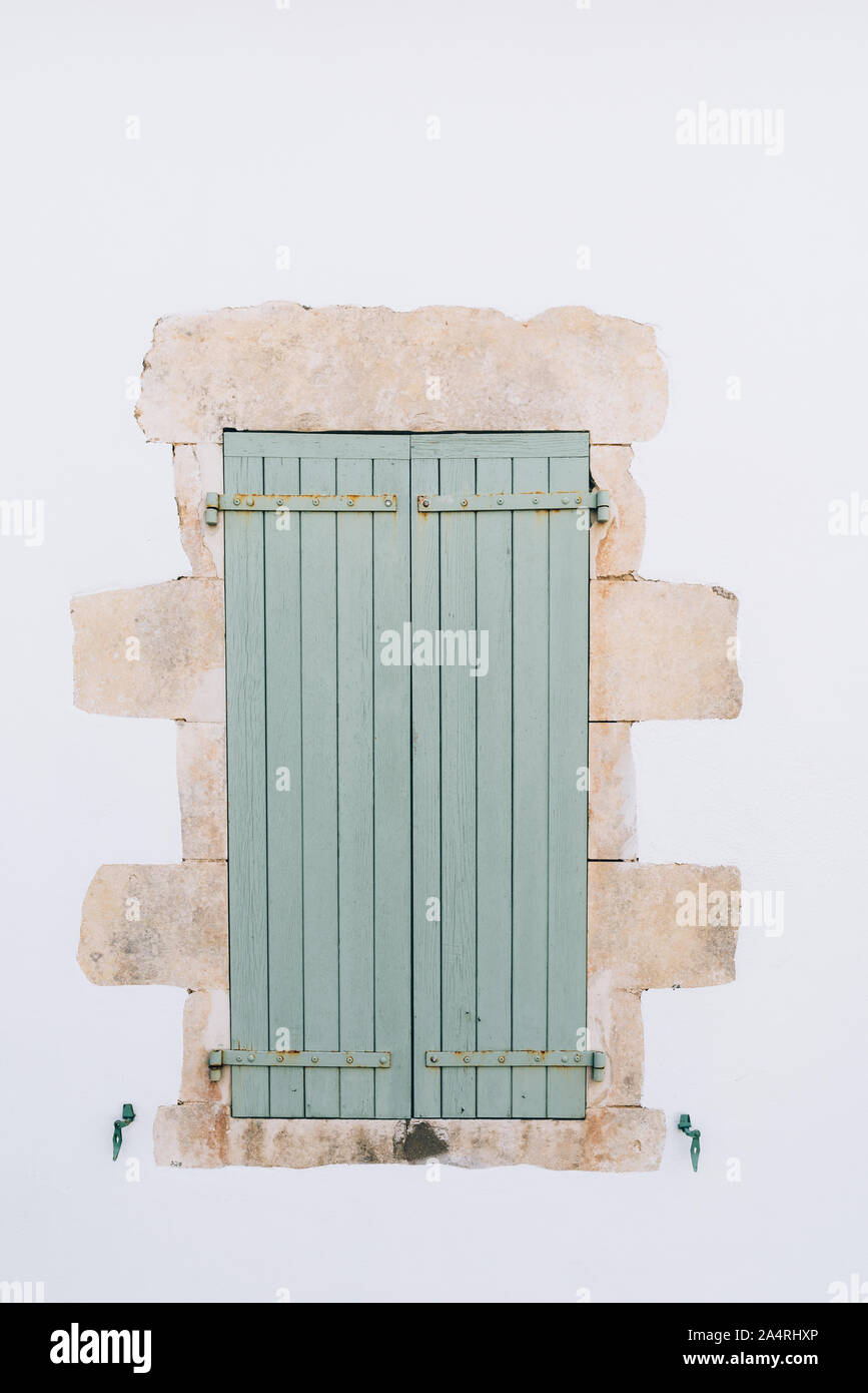 Old window with wooden light green painted closed shutters on white ...