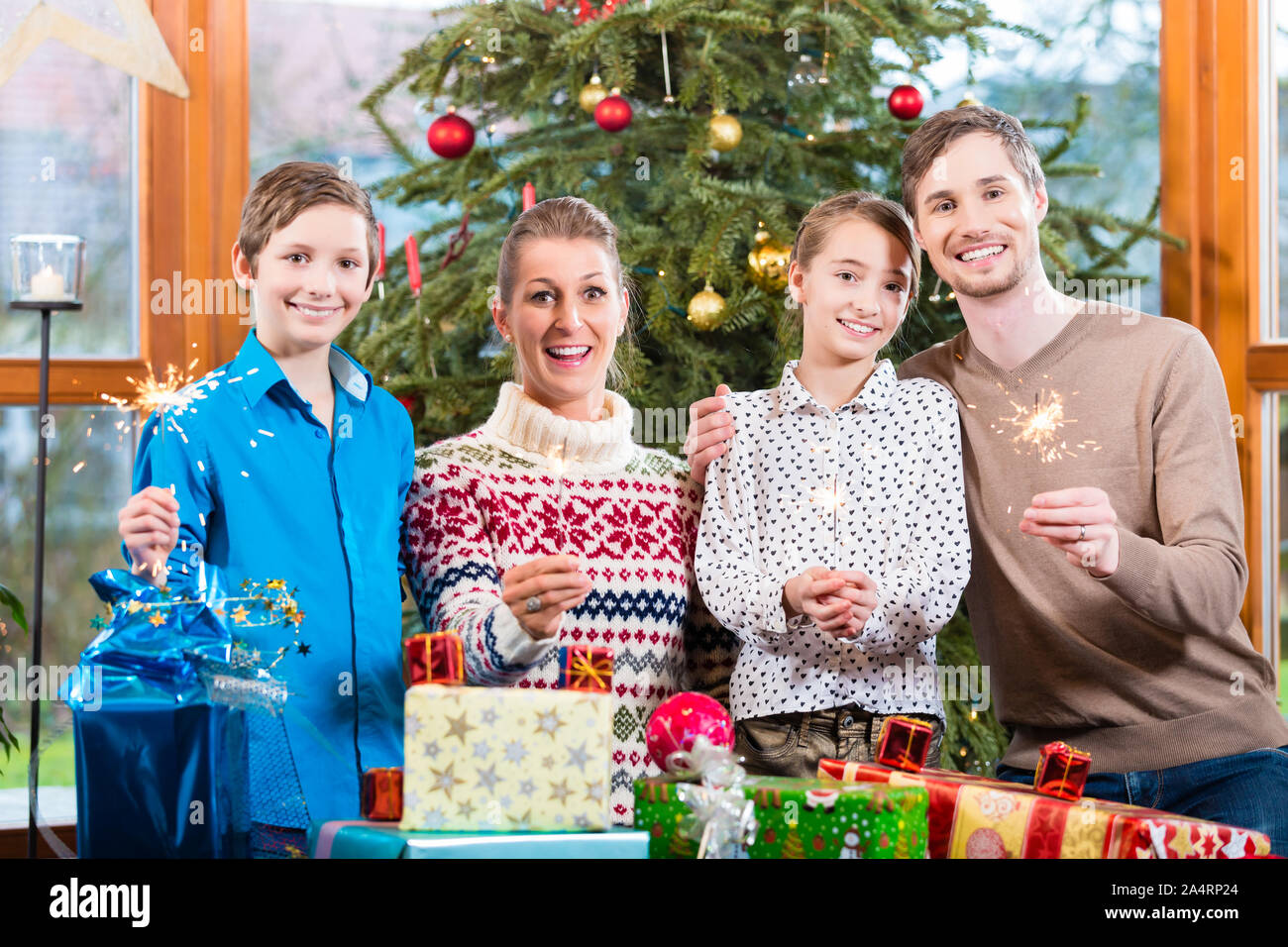 Family of mom, dad and kids with presents under Christmas tree Stock Photo