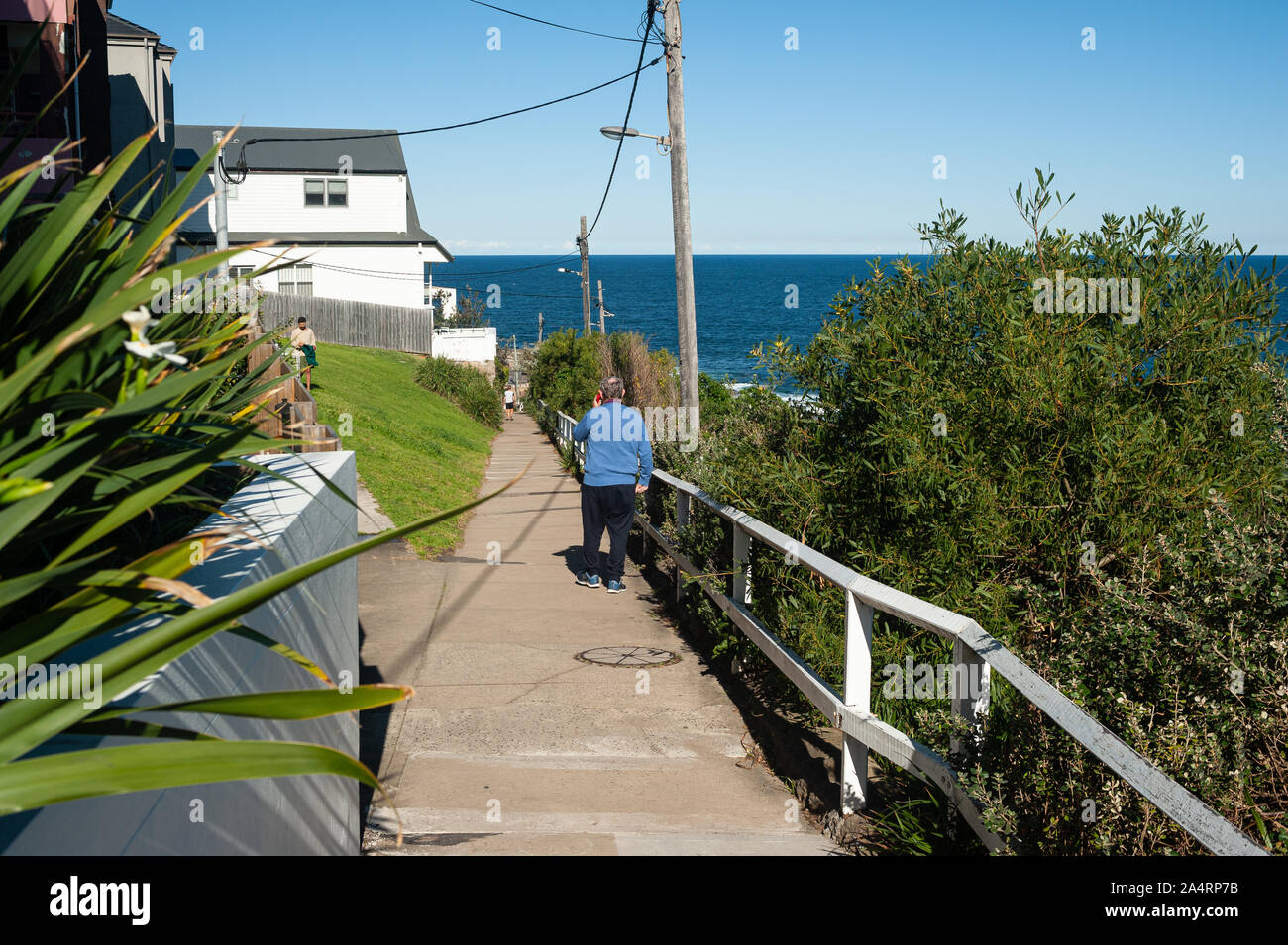 24.09.2019, Sydney, New South Wales, Australia - A man walks by residential houses along the Bondi to Coogee Walk with the sea in the backdrop. Stock Photo