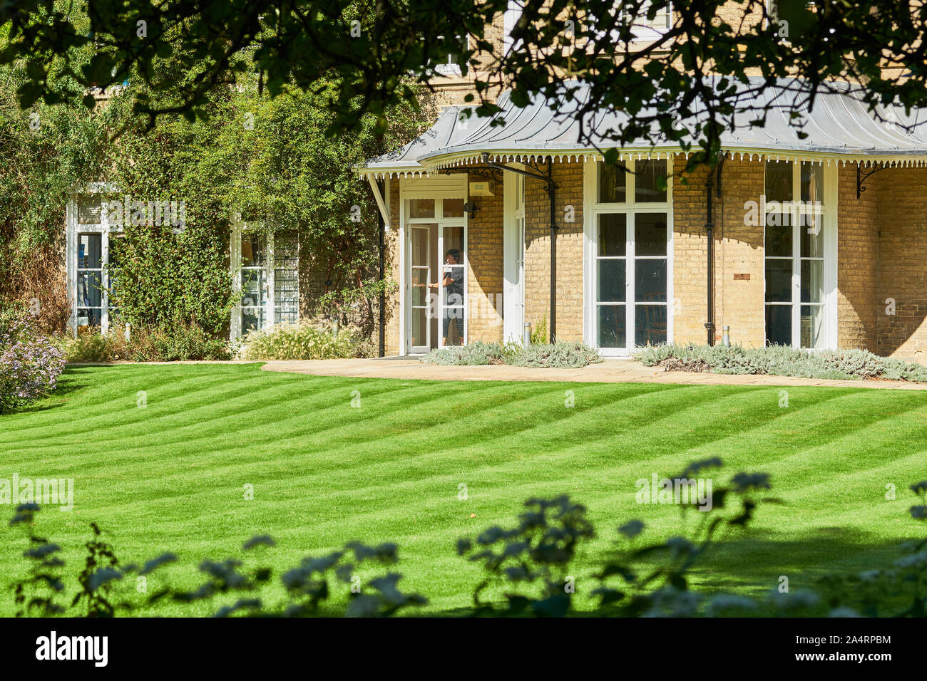 Brookside house and lawn in the university botanic gardens at Cambridge, England, on a sunny
