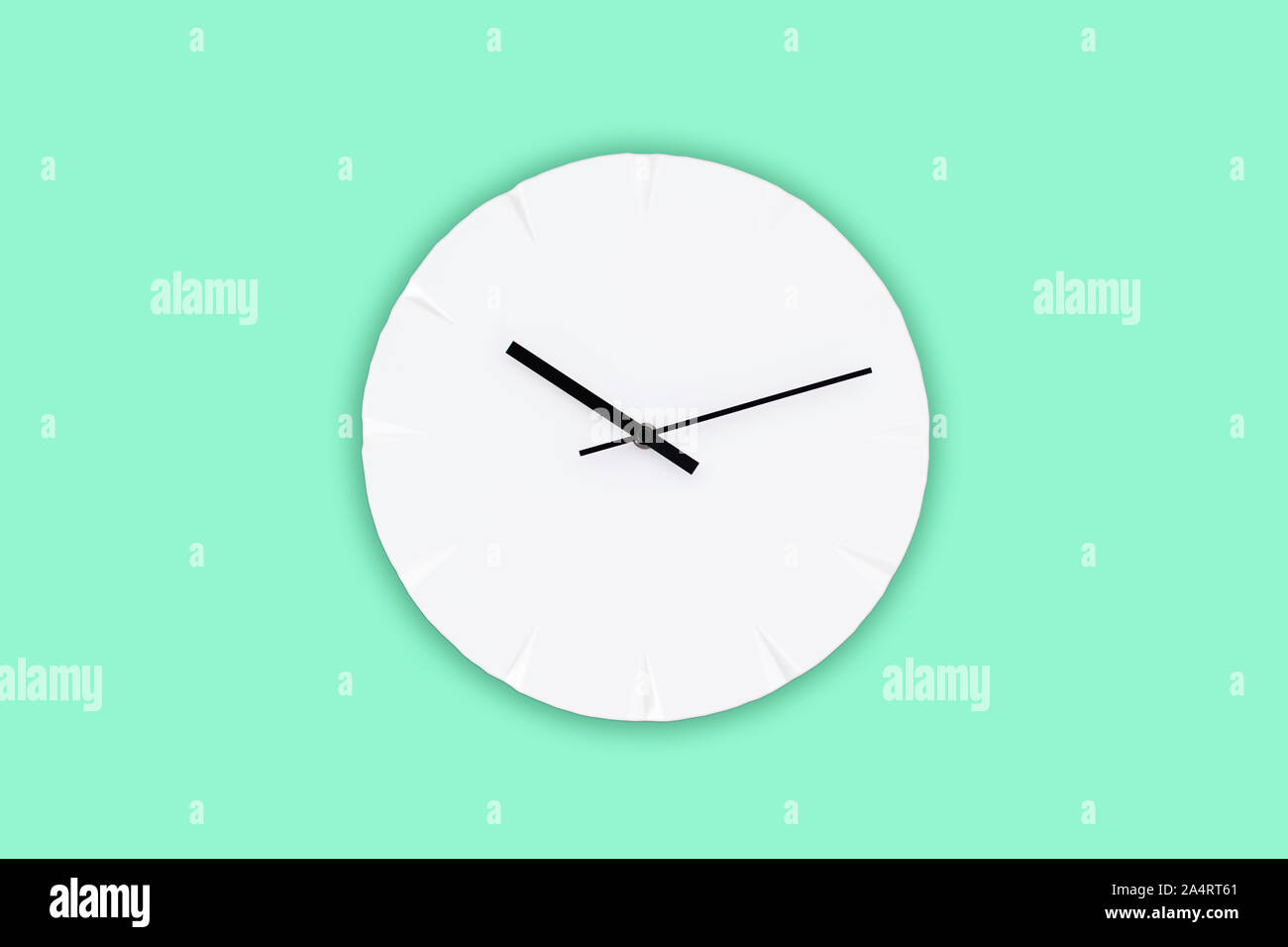 White wall clock with black clock hands hanging on the green mint wall