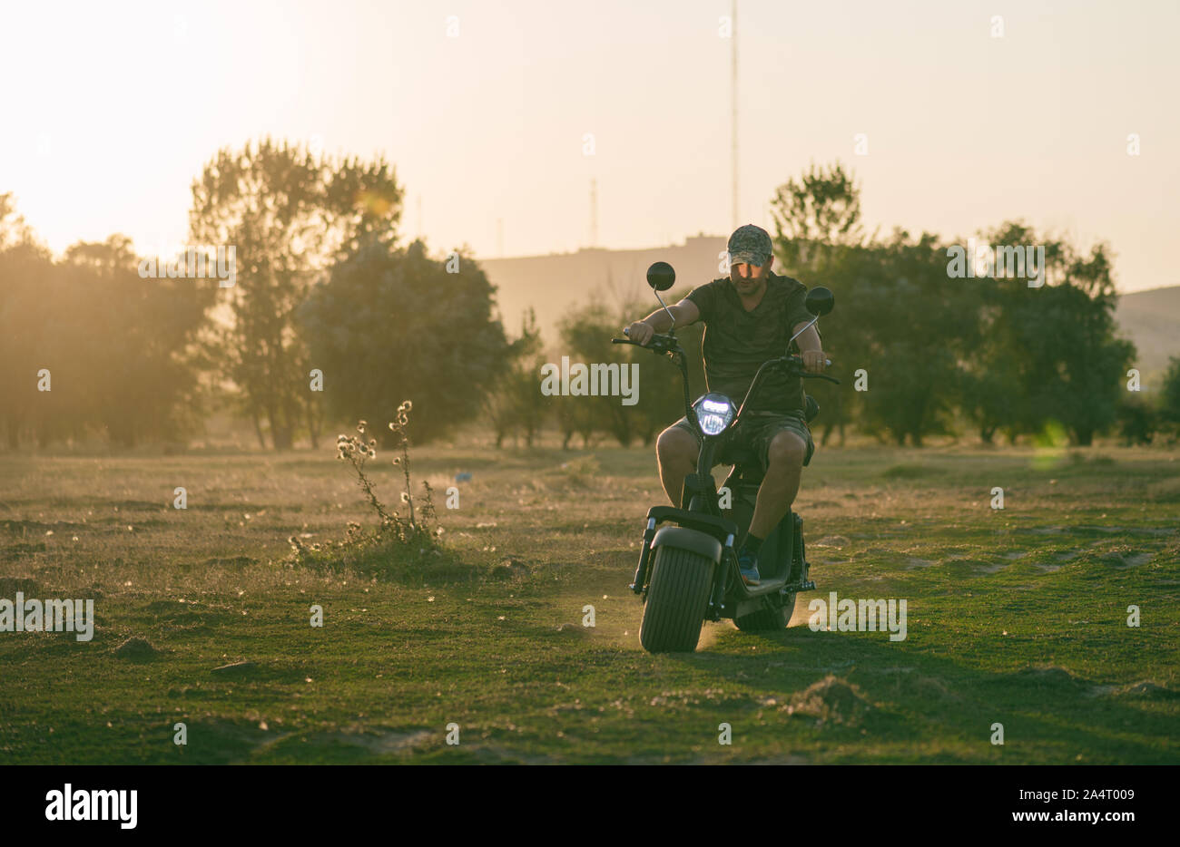 man on a motorized bicycle in sunset time Stock Photo
