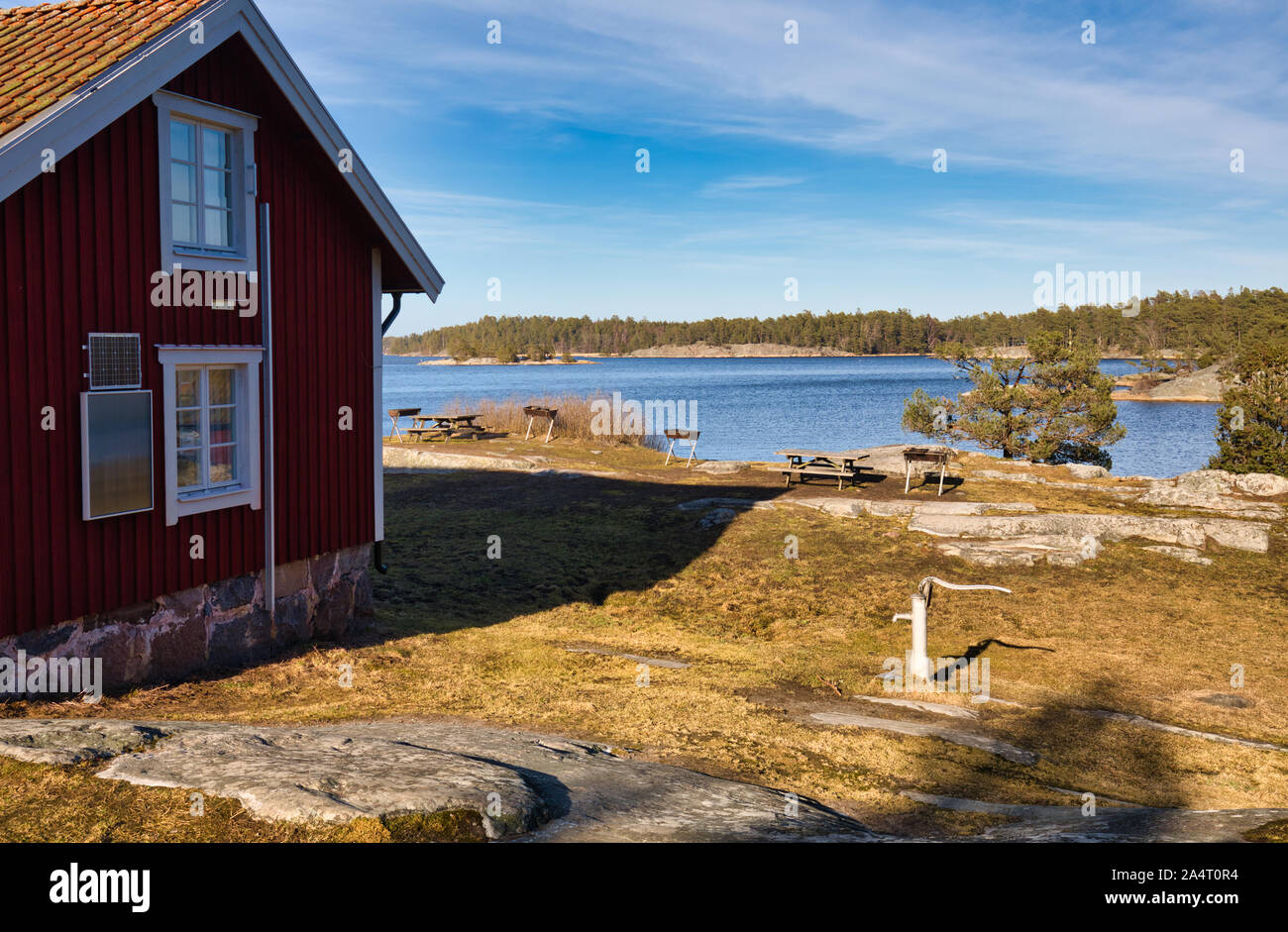 Traditional falu red timber cabin by lake with solar panels, Bjorno ...