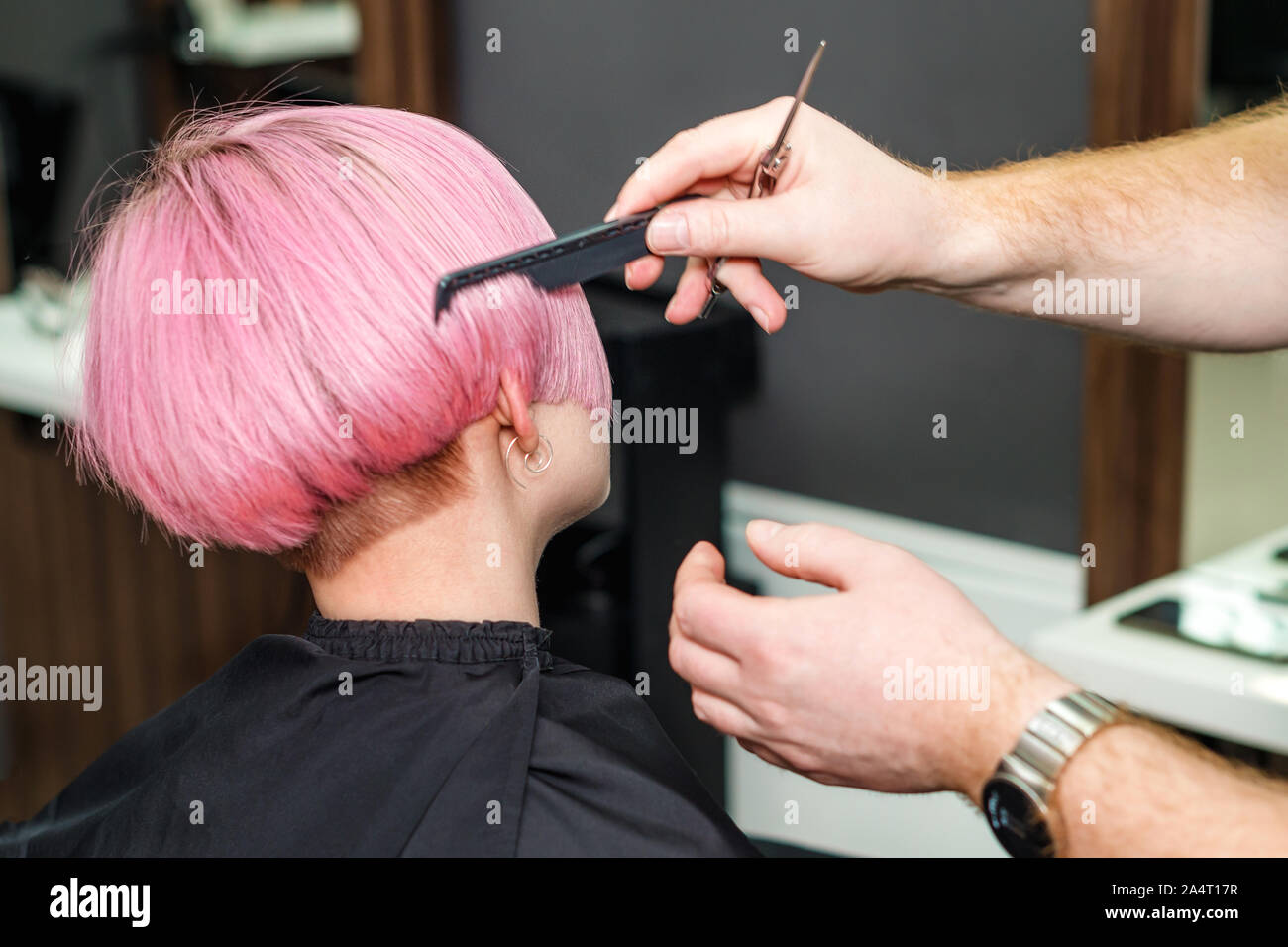 Close up of hairdresser is combing client's pink hair in hair salon