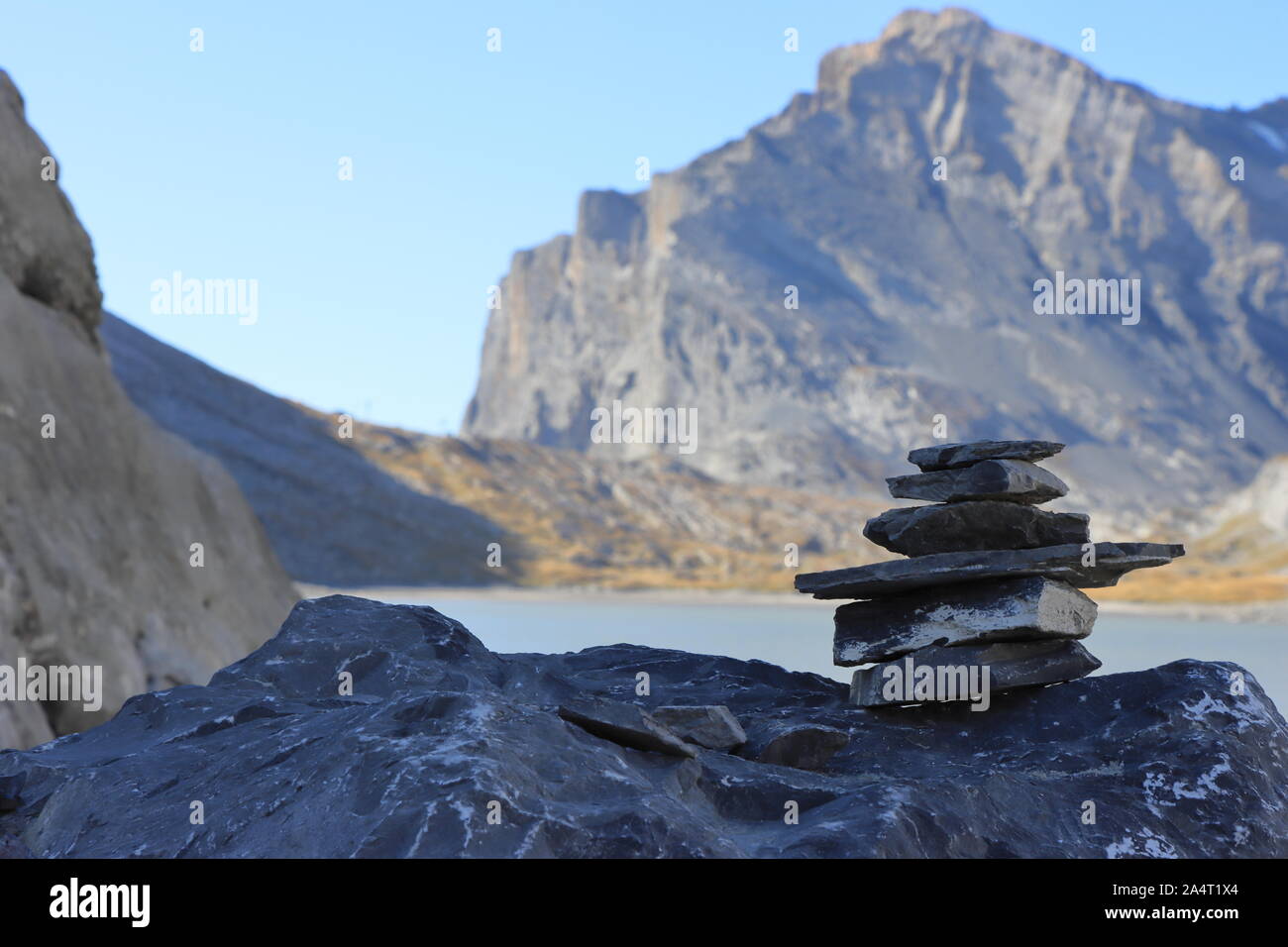 Stone heaps often mark hiking trails in the alps. The lake in the background is the Daubensee, a mountain lake close to Leukerbad. Stock Photo