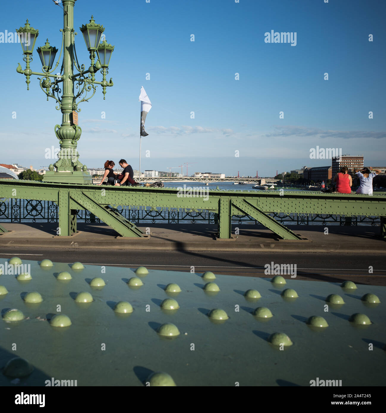 SZABADSAG HID BRIDGE BUDAPEST - 1894-1896 DESIGNED BY ARCHITECT JANOS FEKETEHAZY - LOVERS SEATING ON THE IRON BRIDGE STRUCTURE DURING A SUNNY DAY - BUDAPEST CITY - BUDAPEST BRIDGE - BUDAPEST STREET PHOTOGRAPHY - HUNGARY © Frédéric BEAUMONT Stock Photo