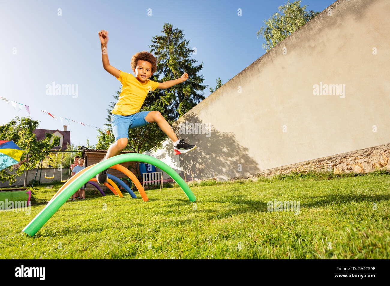 Happy black boy jump over sequence of obstacles on the backyard