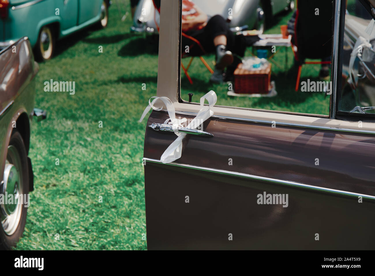 Ribbon tied to classic car door with people eating from hamper in background, Autokarna 2019, Wollaton Park, Nottingham, east Midlands, England Stock Photo