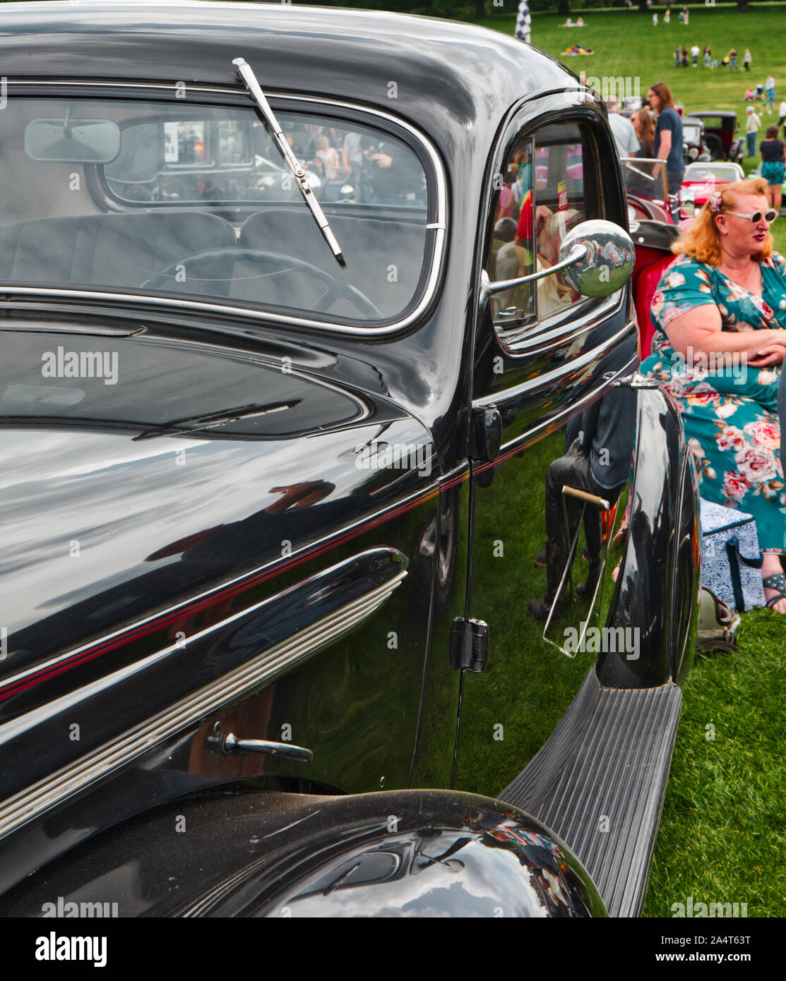 Woman in retro dress and sunglasses sitting by classic vintage car, Nottingham Transport Festival, Autokarna 2019, Wollaton Park, Nottingham, England Stock Photo