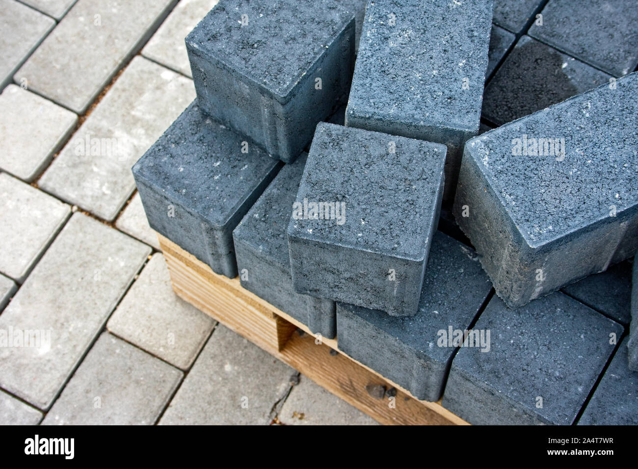 Dark grey paving stones for road works on wooden pallets, below light-coloured paving stones Stock Photo