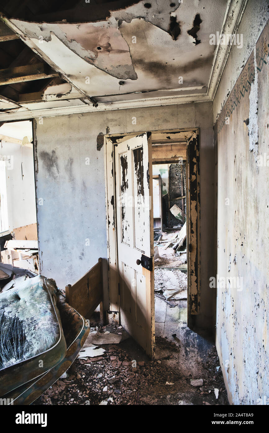 Interior of abandoned croft with mattress, damp, collapsing ceiling and view through internal door, Isle of Lewis and Harris, Outer Hebrides, Scotland Stock Photo