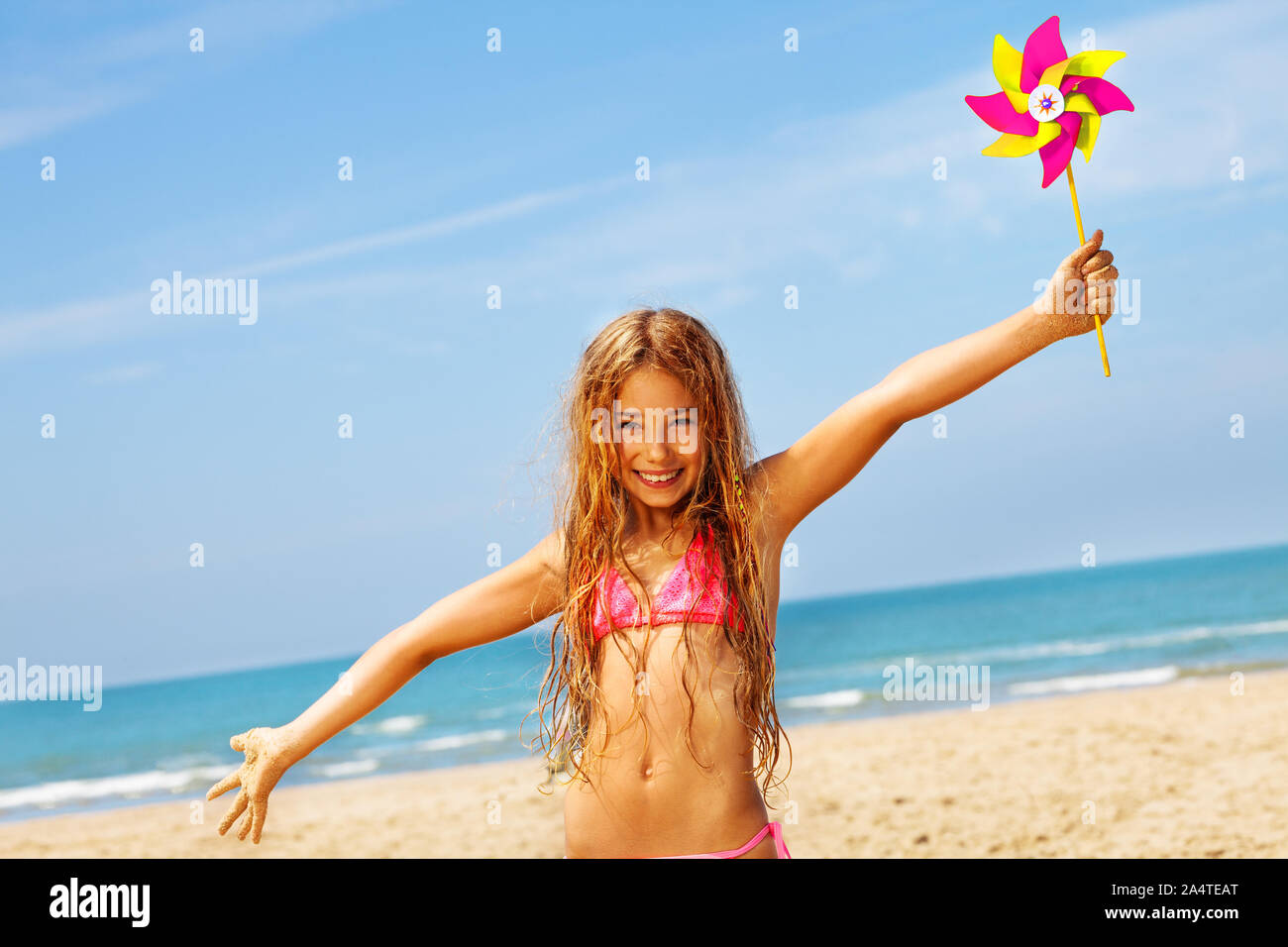 Happy Portrait Of Smiling Girl With Pinwheel And Wide Spread Hands Standing On The Sea Beach Stock Photo Alamy