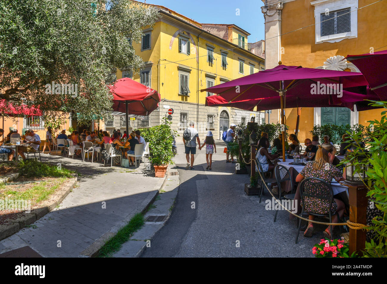 Street view of the historic centre of the famous town of Pisa with outdoor restaurants full of people and tourists lunching in summer, Tuscany, Italy Stock Photo