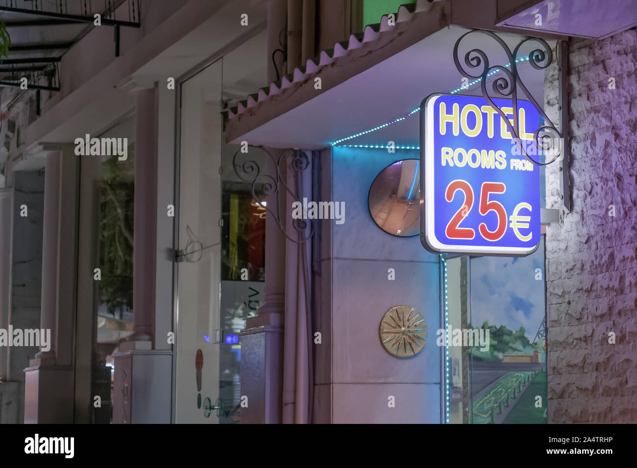Nightlife hotel entrance sign with rooms price. Illuminated view of bright sign with displaying message of hotel rooms from 25 euros in Thessaloniki. Stock Photo