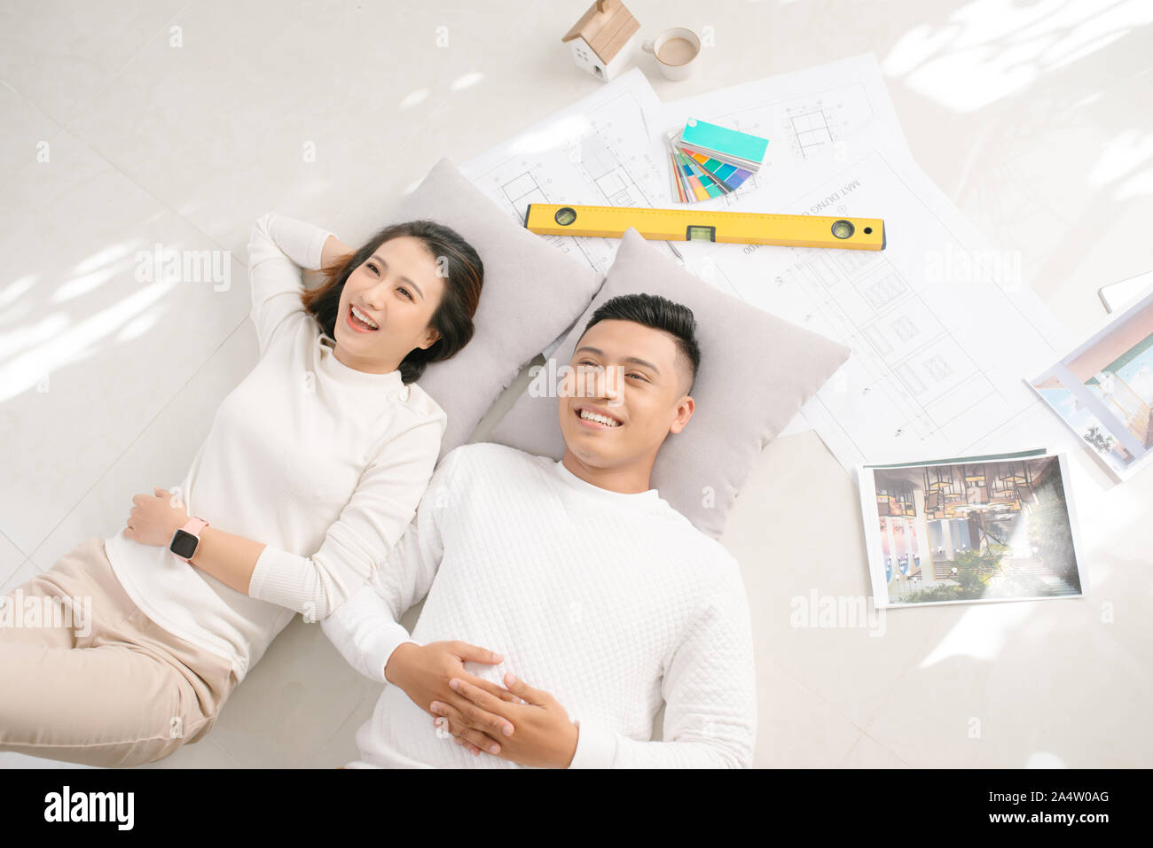A young couple lying on the floor of their new home, think about their new interior decoration Stock Photo