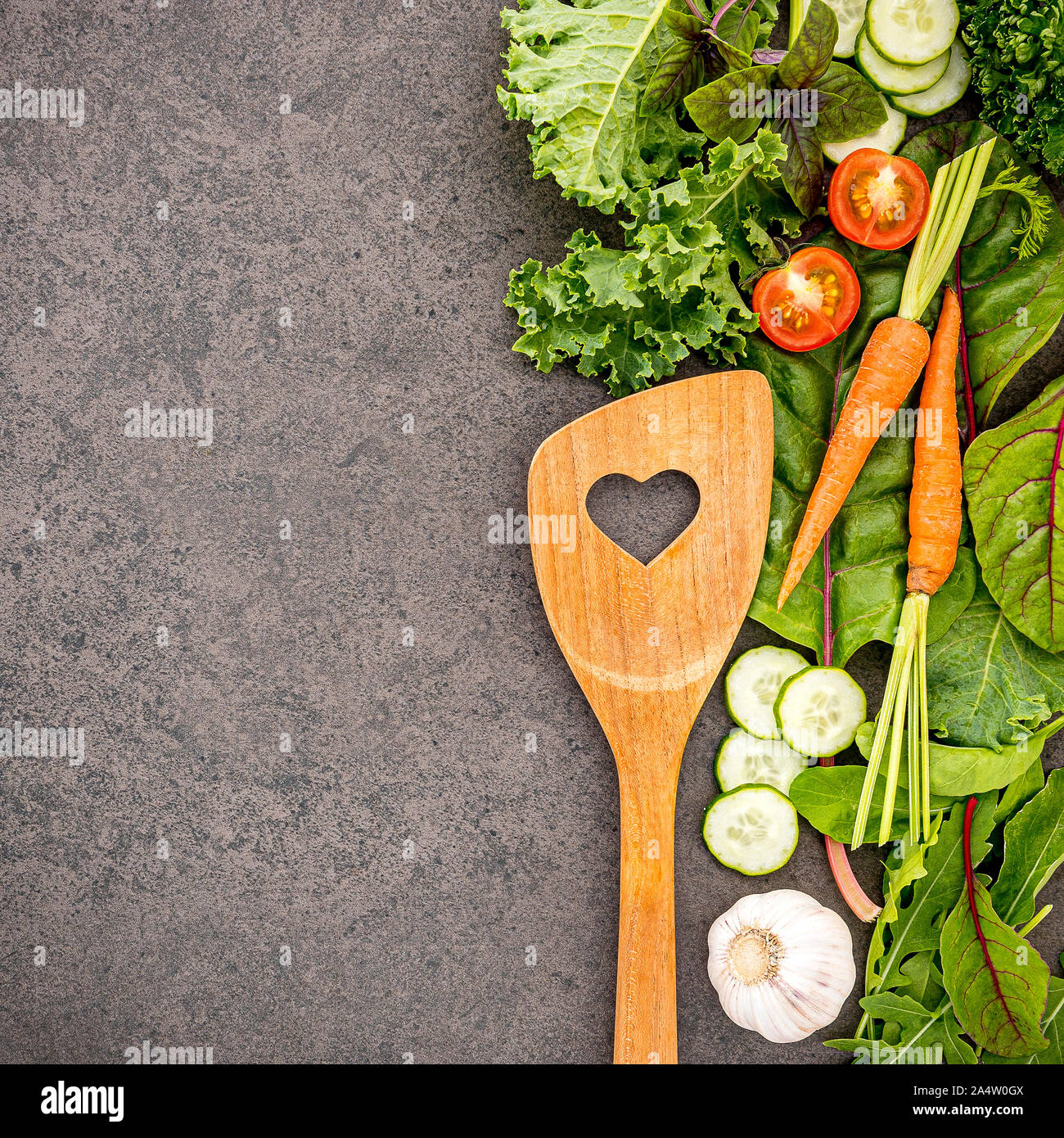 Wooden spoon and vegetables on dark stone background. Healthy food and ...