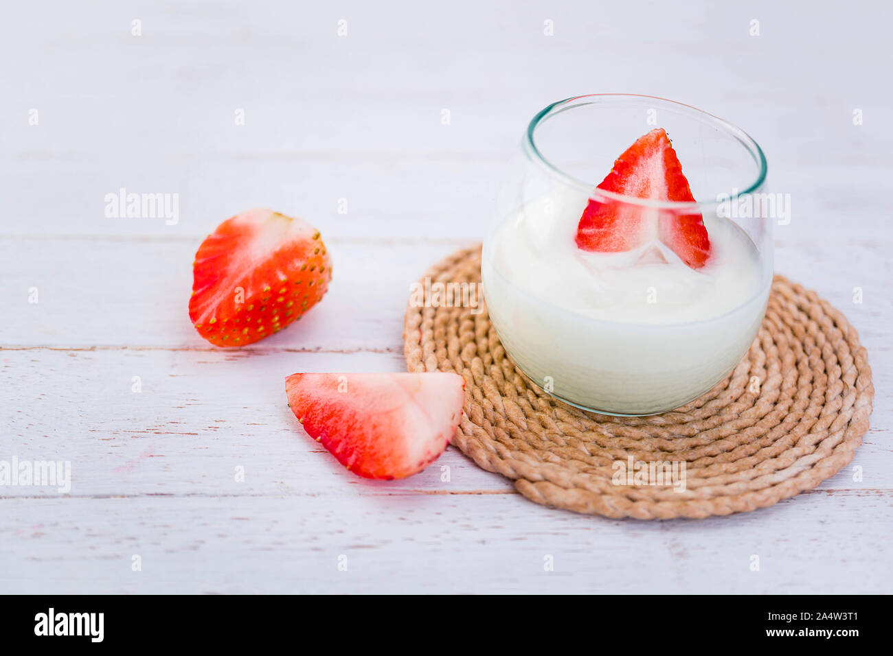 Original flavor yogurt with fresh strawberry in clear glass on white