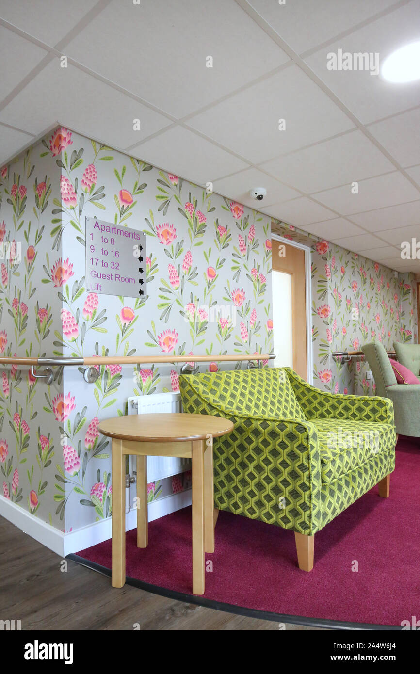 Interior of the entrance lobby in a newly refurbished care home near Wakefield, UK. Shows bright wallpaper, armchairs and day room beyond (right) Stock Photo