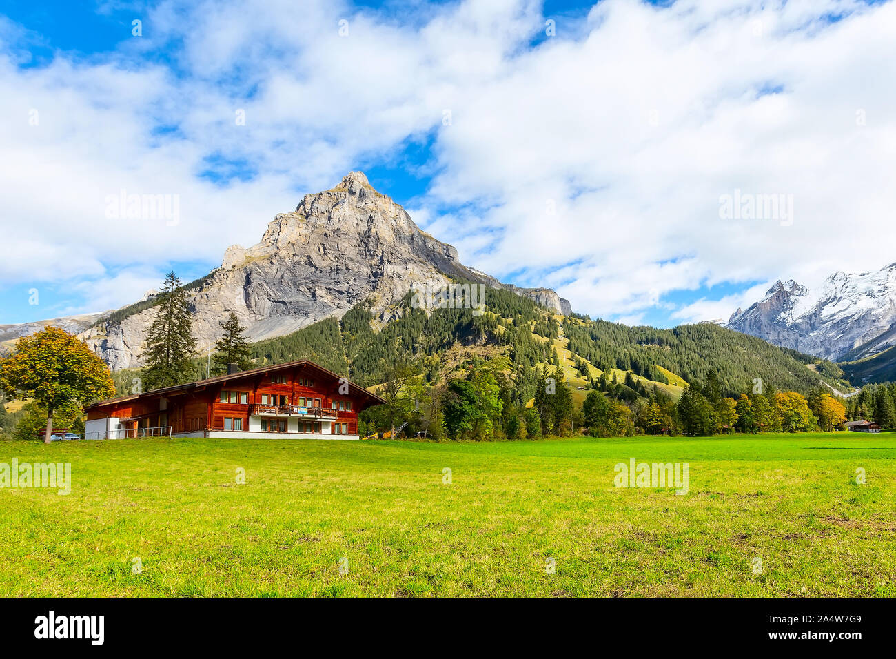 Wooden chalet in Kandersteg village, Canton Bern, Switzerland, Europe, Autumn trees and mountains panorama Stock Photo