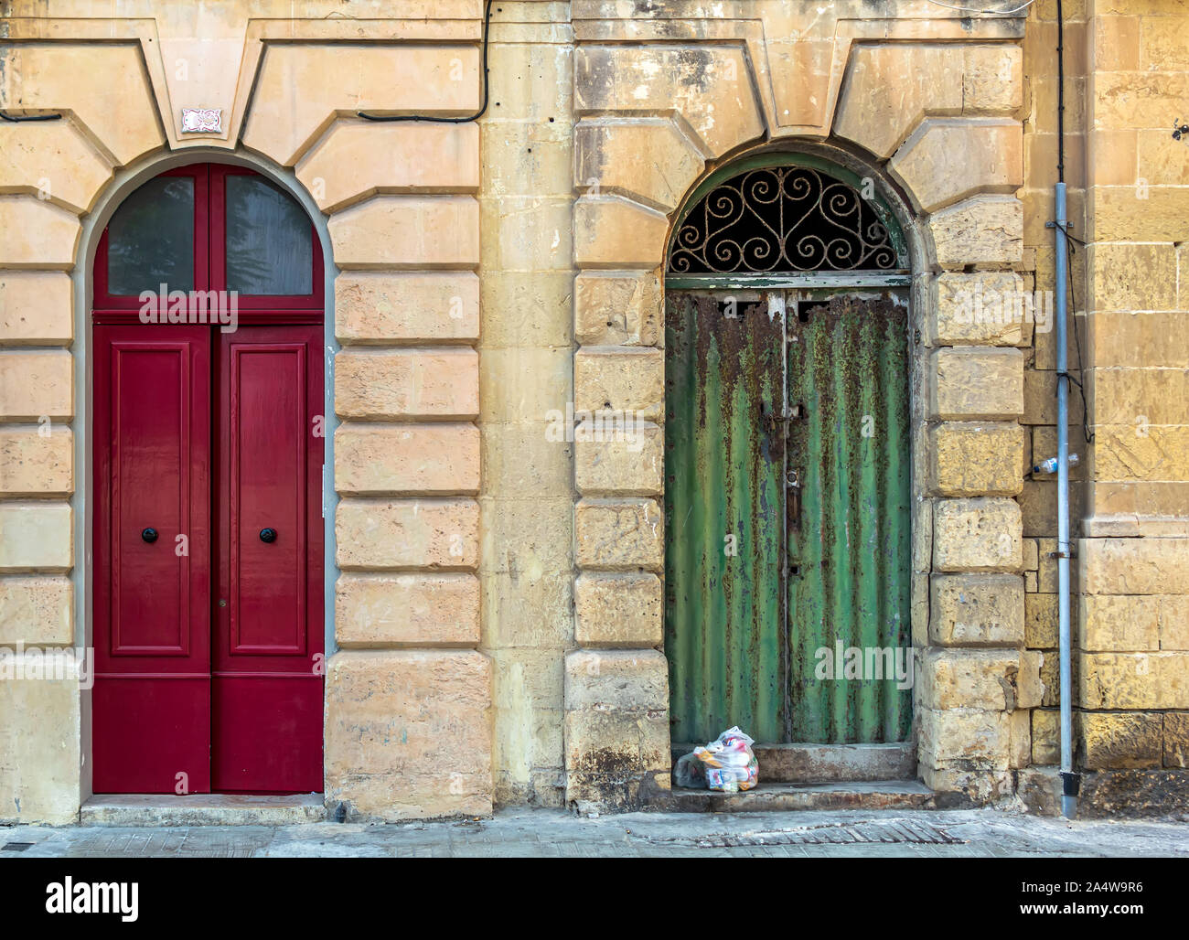 Two vintage arched doors. Old fashioned red door and run-down green door. Retro entry doors in Valletta, Malta. Stock Photo