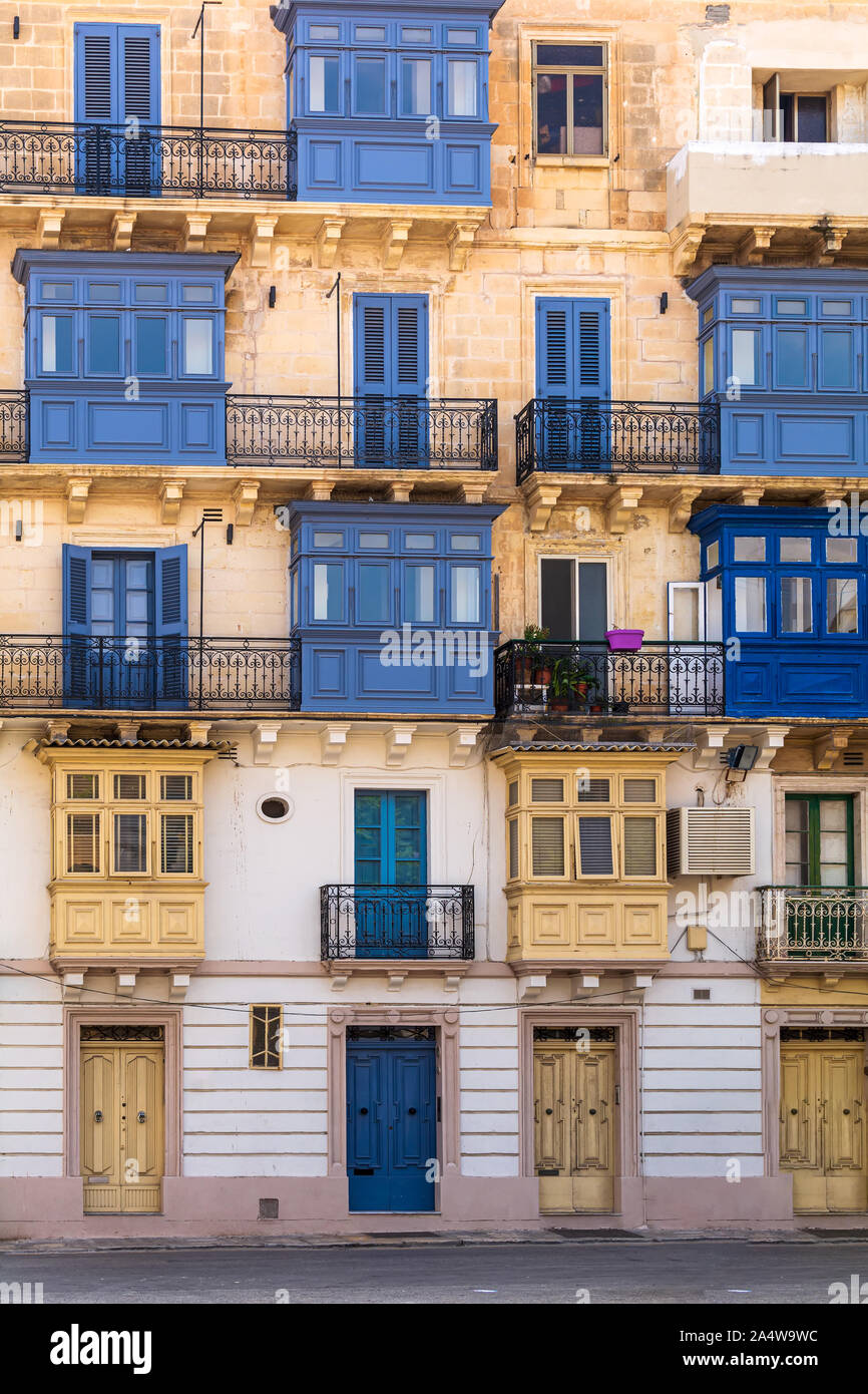 Residential house facade with blue door, window shutters and traditional Maltese wooden enclosed balcony in Valletta, Malta. Stock Photo