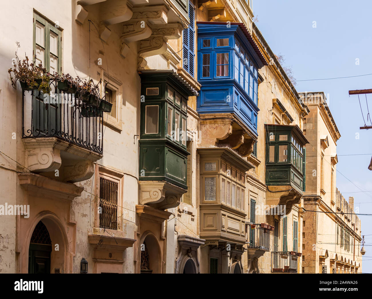 Residential house facade with traditional Maltese multicolored enclosed wooden balconies in Valletta, Malta, in evening sunlight. Stock Photo