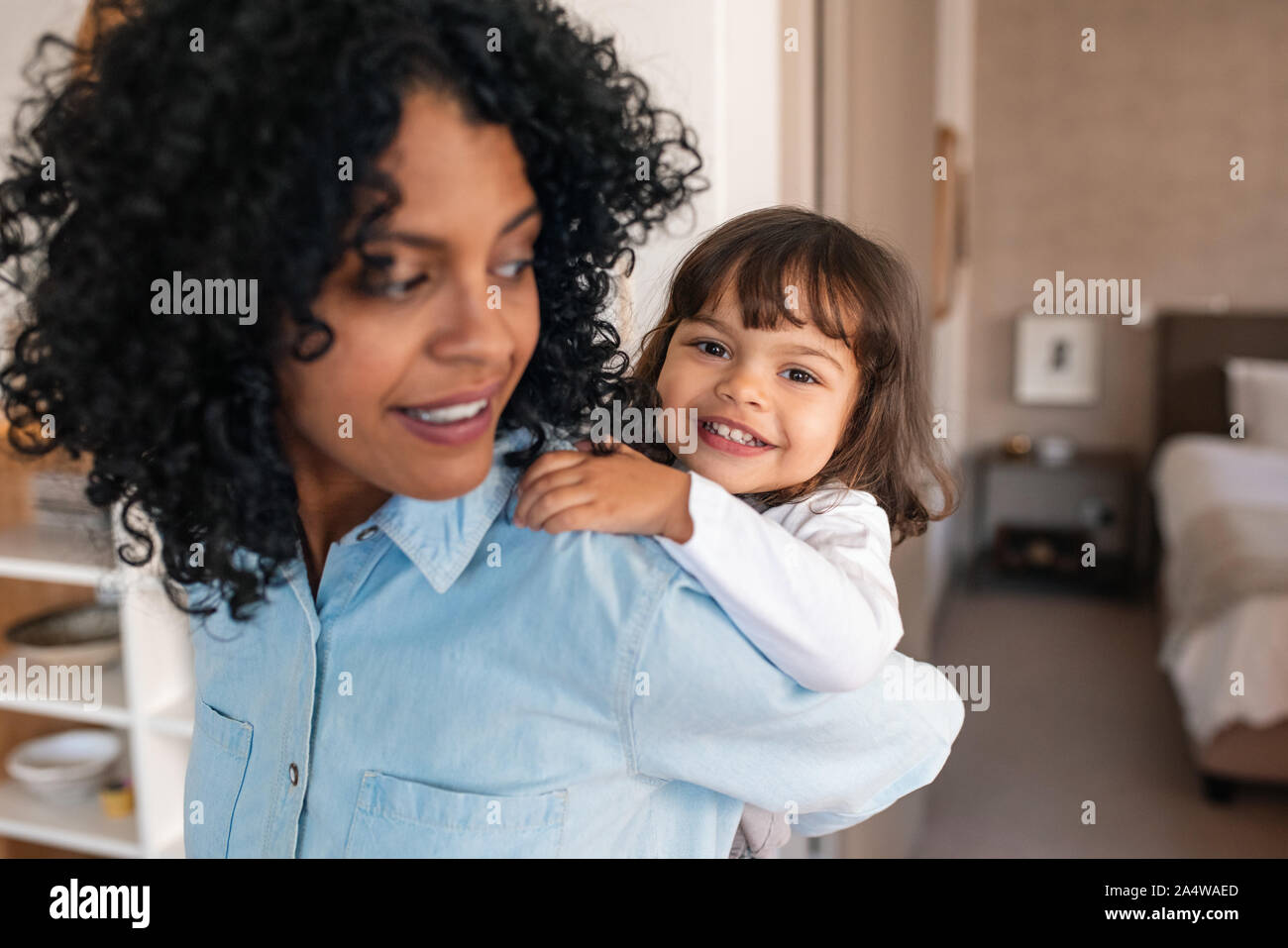 Cute little girl getting a piggyback from her smiling mom Stock Photo