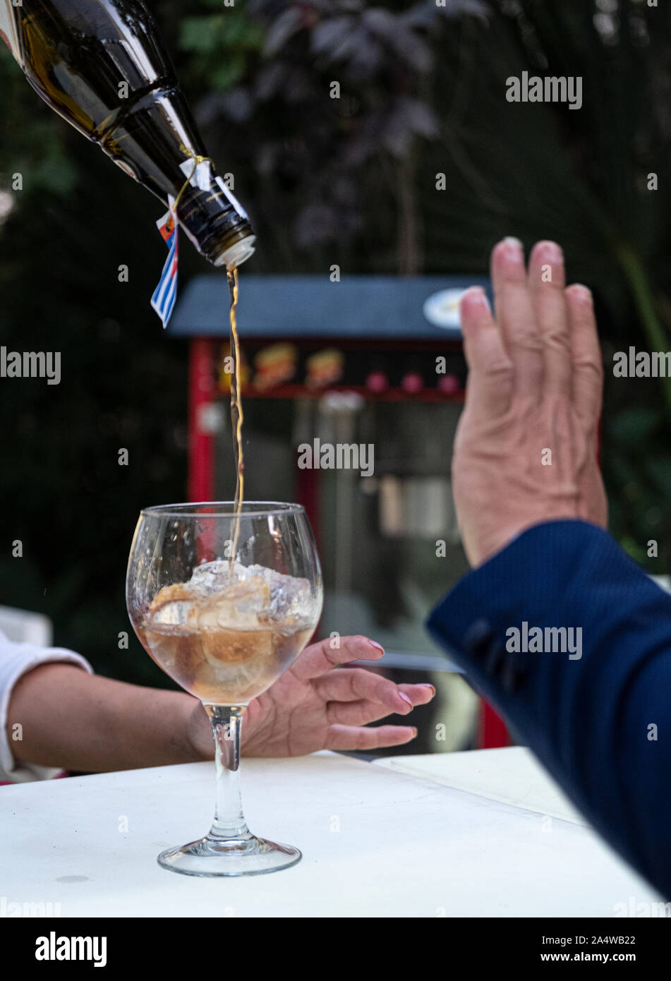 Waitress putting a glass of rum on a glass with ice. alcoholism concept Stock Photo