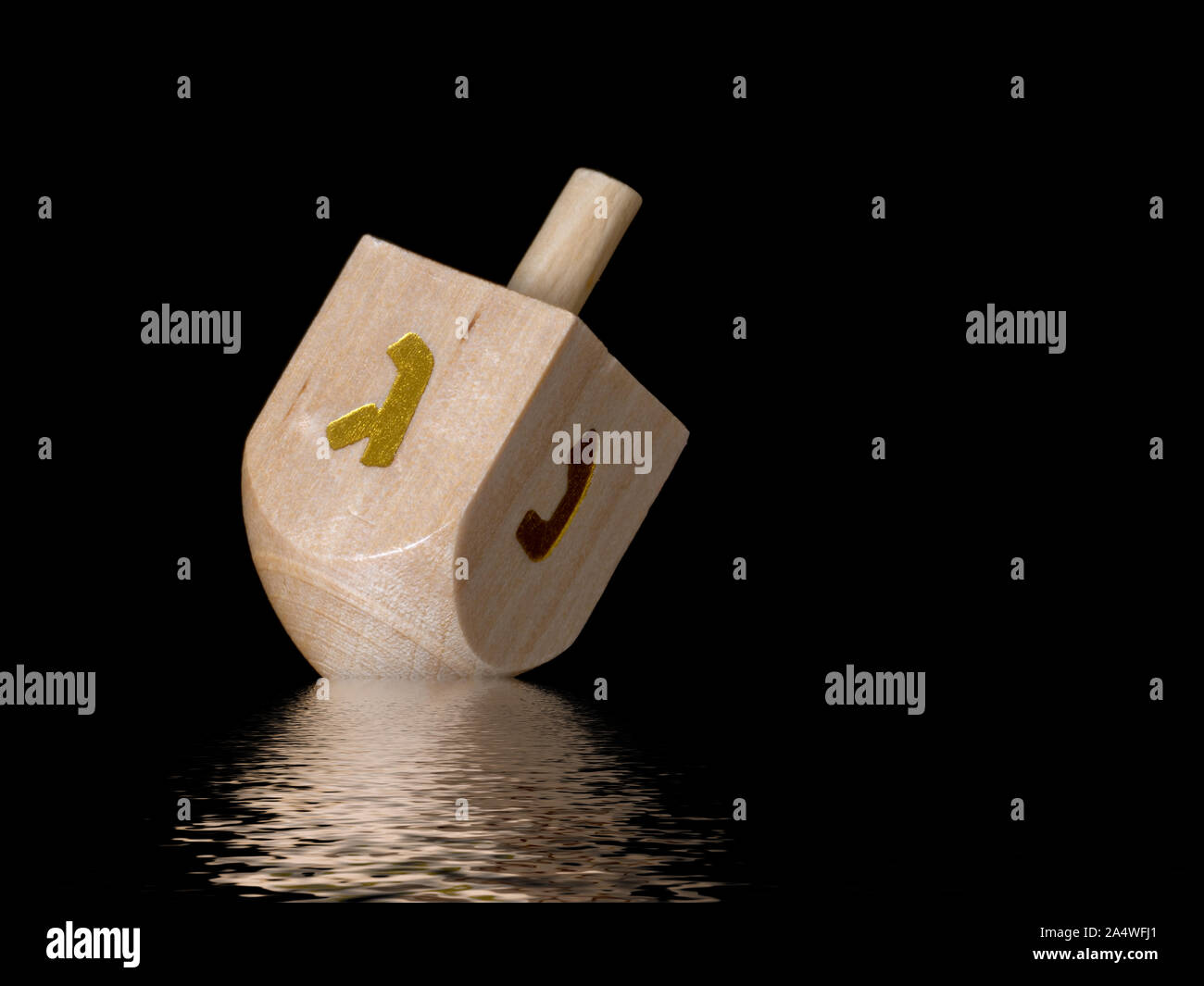 Dreidel on black with reflection. Judaism, religious equipment, item. Stock Photo