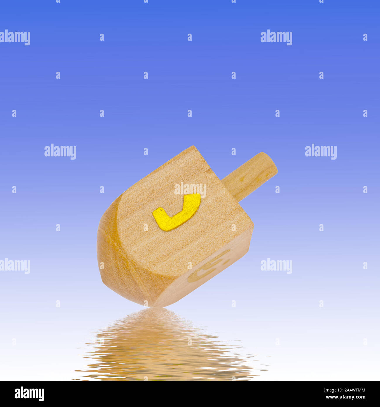 Dreidel on bright background, blue, reflection. Judaism, religious equipment, item. Stock Photo