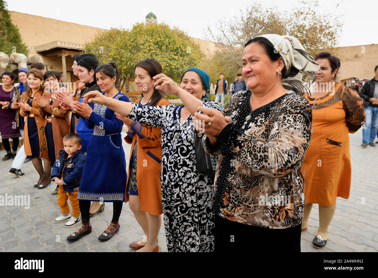 Dancing guests during a wedding in the main street of the old town of Khiva, a very popular site for all the festivities in the town. Uzbekistan Stock Photo