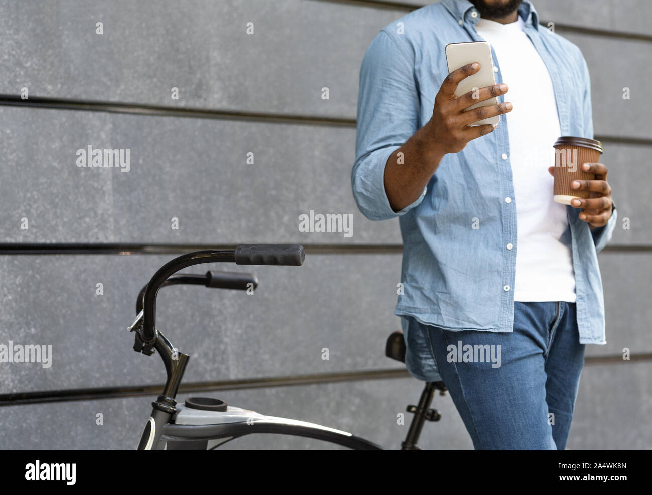 Unrecognizable man with bicycle using smartphone and drinking coffee outdoors Stock Photo