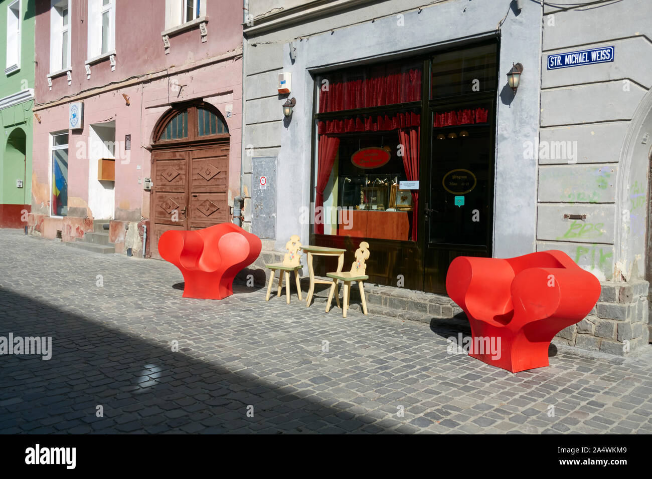 Distinctive red armchairs outside the Deliciile Kronstadt patiserie, Brasov, Transylvania, Romania. Stock Photo