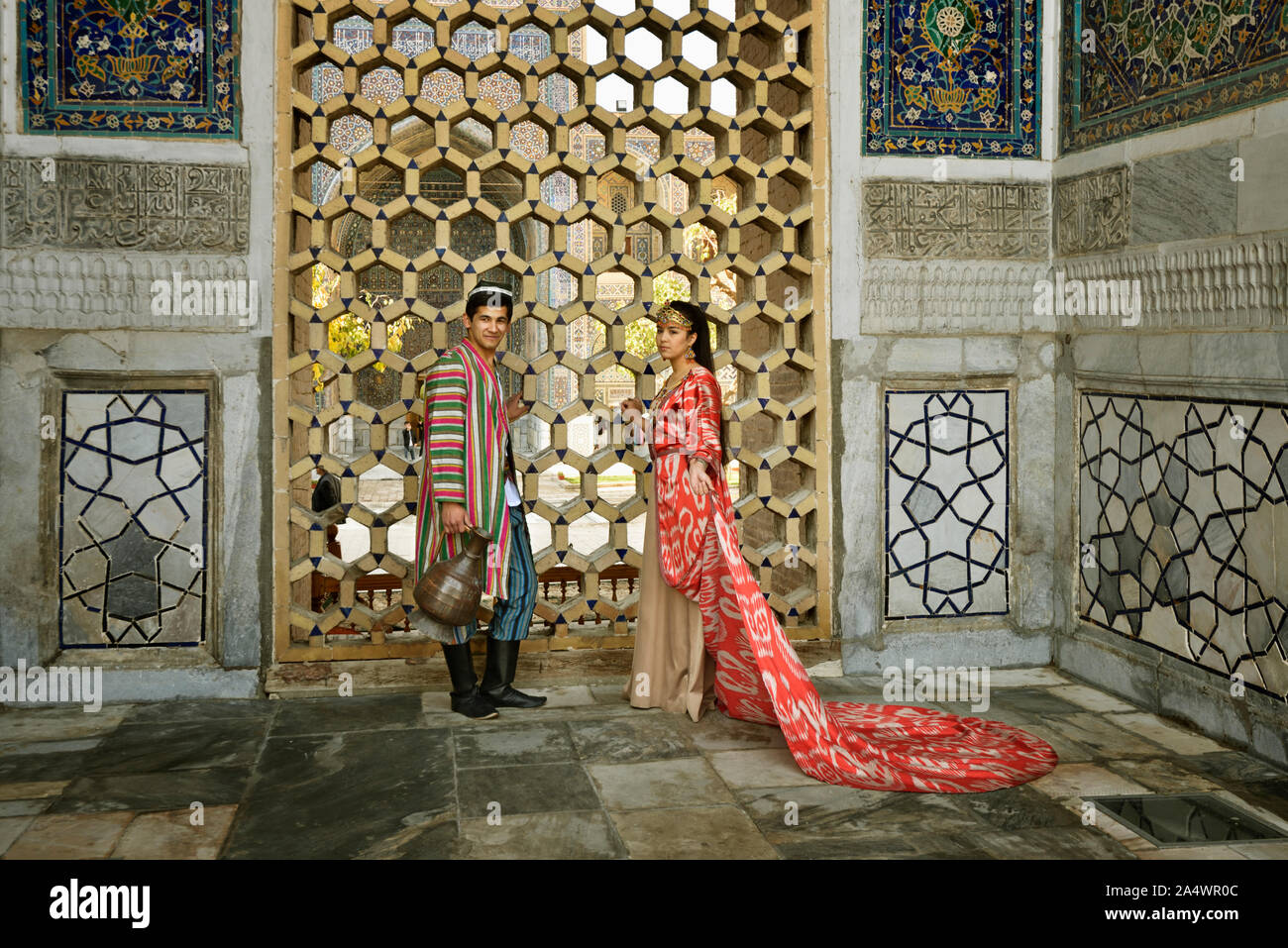 The bride and the groom wearing the traditional outfits for the wedding. Registan square, a UNESCO World Heritage Site, Samarkand. Uzbekistan Stock Photo