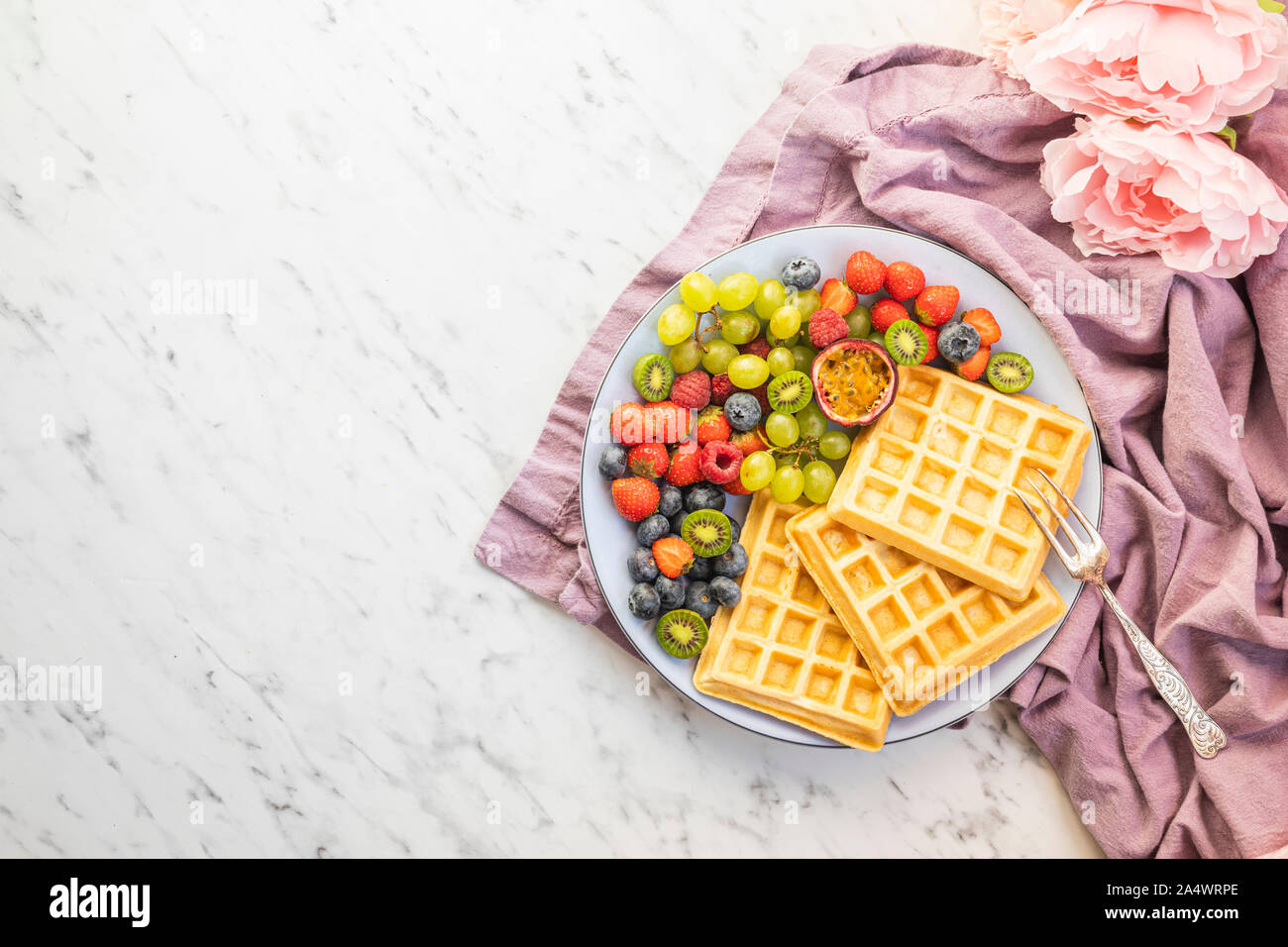 https://c8.alamy.com/comp/2A4WRPE/a-plate-with-fresh-fruit-and-belgian-waffles-the-fruits-are-mini-kiwi-strawberries-passion-fruit-grapes-raspberries-and-blueberries-with-a-purpl-2A4WRPE.jpg