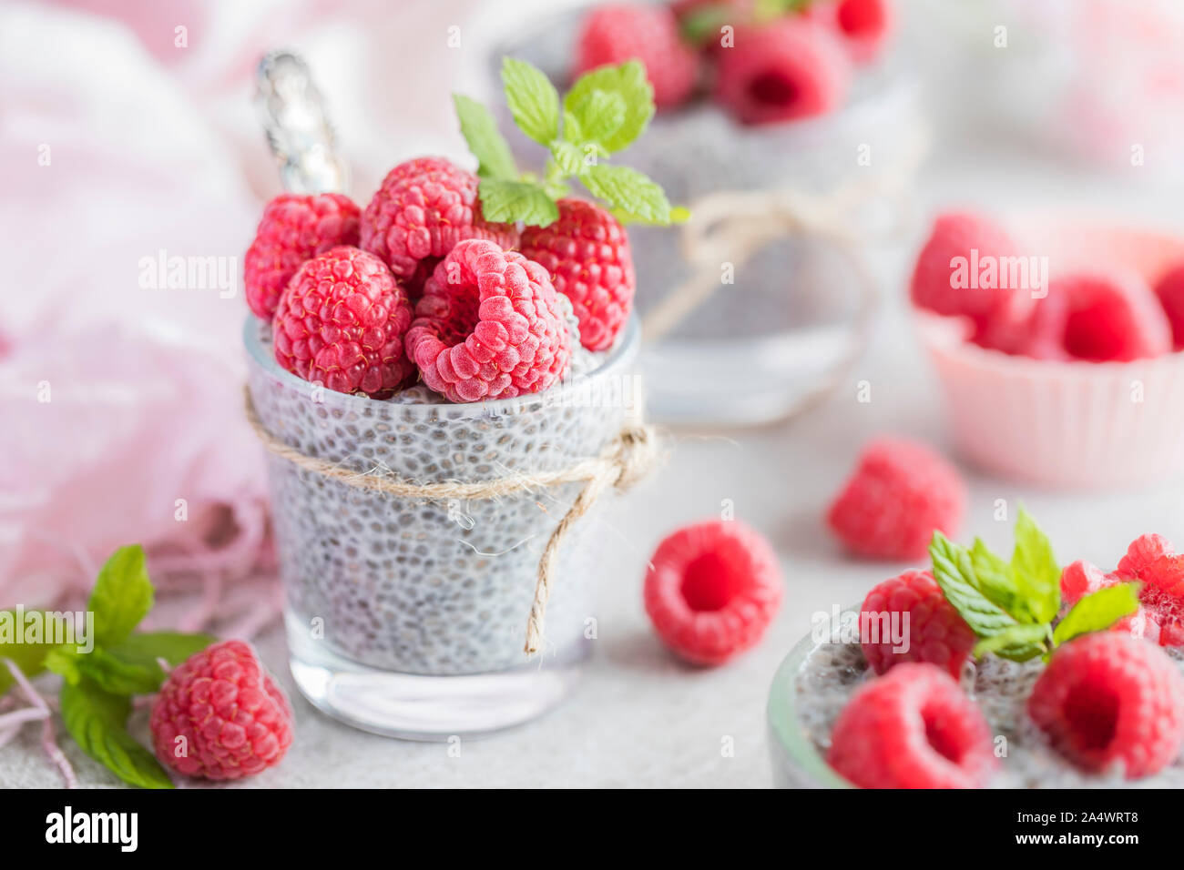 Fresh Chia pudding with fresh raspberries. The pudding is made of Chia seeds, almond milk and agave syrup and is decorated with lemon balm and mint le Stock Photo