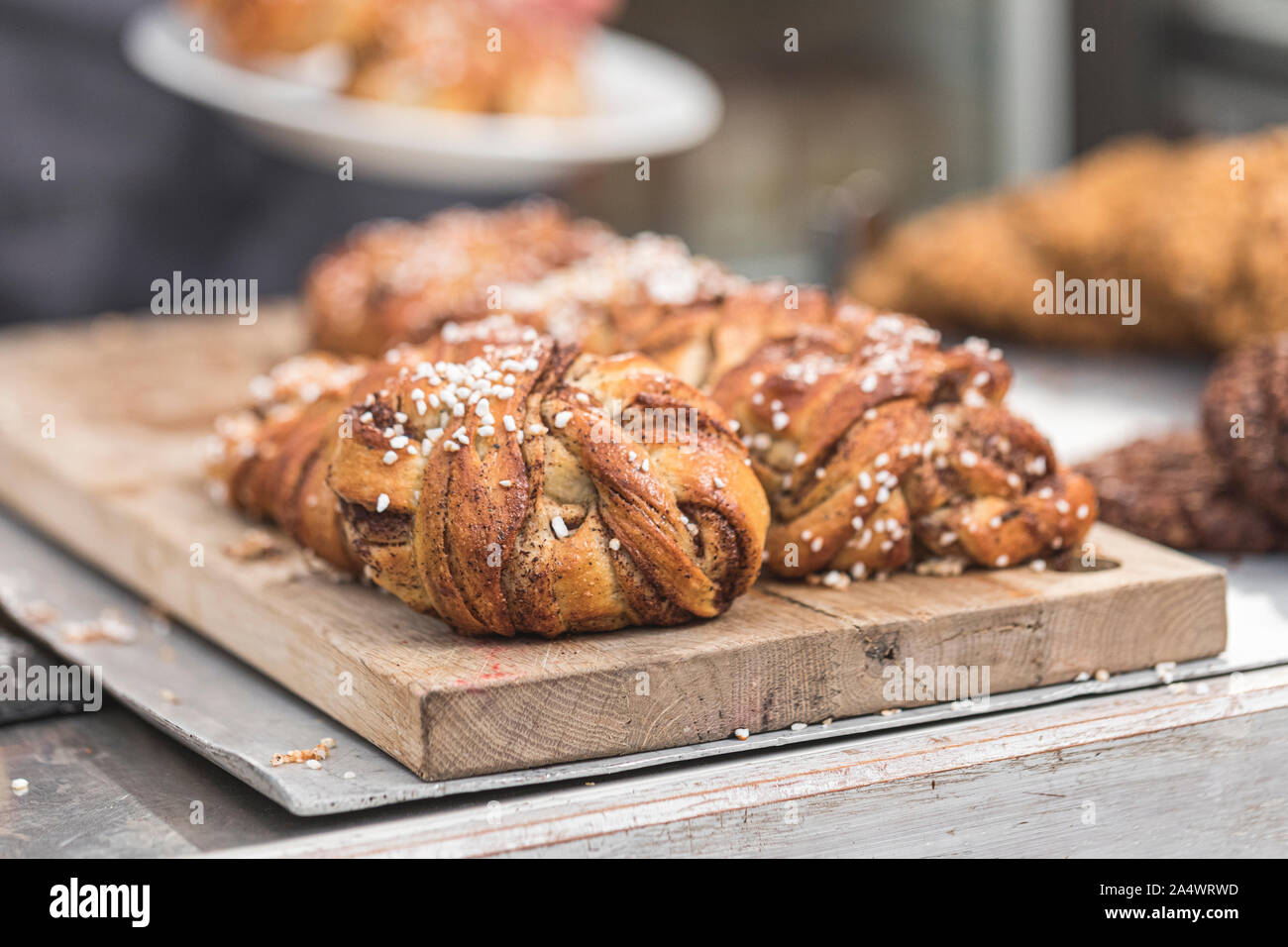 Twisted traditional Swedish cinnamon rolls  at a café. The sweet buns are on a wooden chopping board. Stock Photo