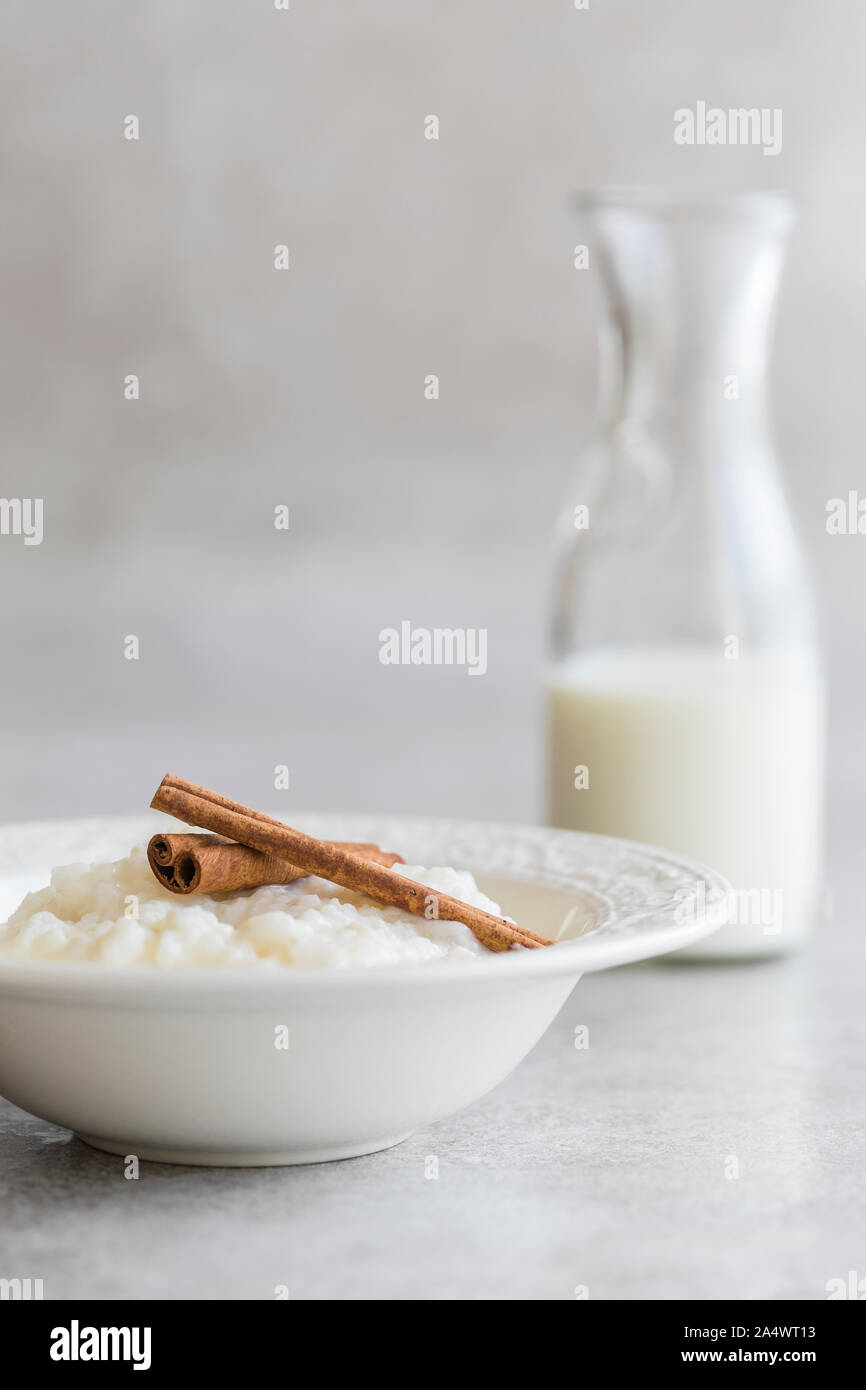 Rice pudding with cinnamon and a bottle of milk. Shot on a gray background with copy space. Stock Photo