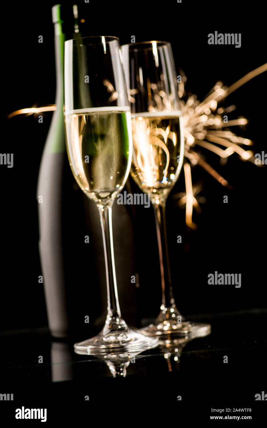 Two champagne glasses and bottle in front of fireworks on black background Stock Photo
