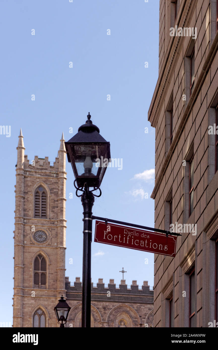 Ruelle de Fortifications street sign and lantern with Notre Dame Basilica in the background, Old Montreal, Quebec, Canada Stock Photo