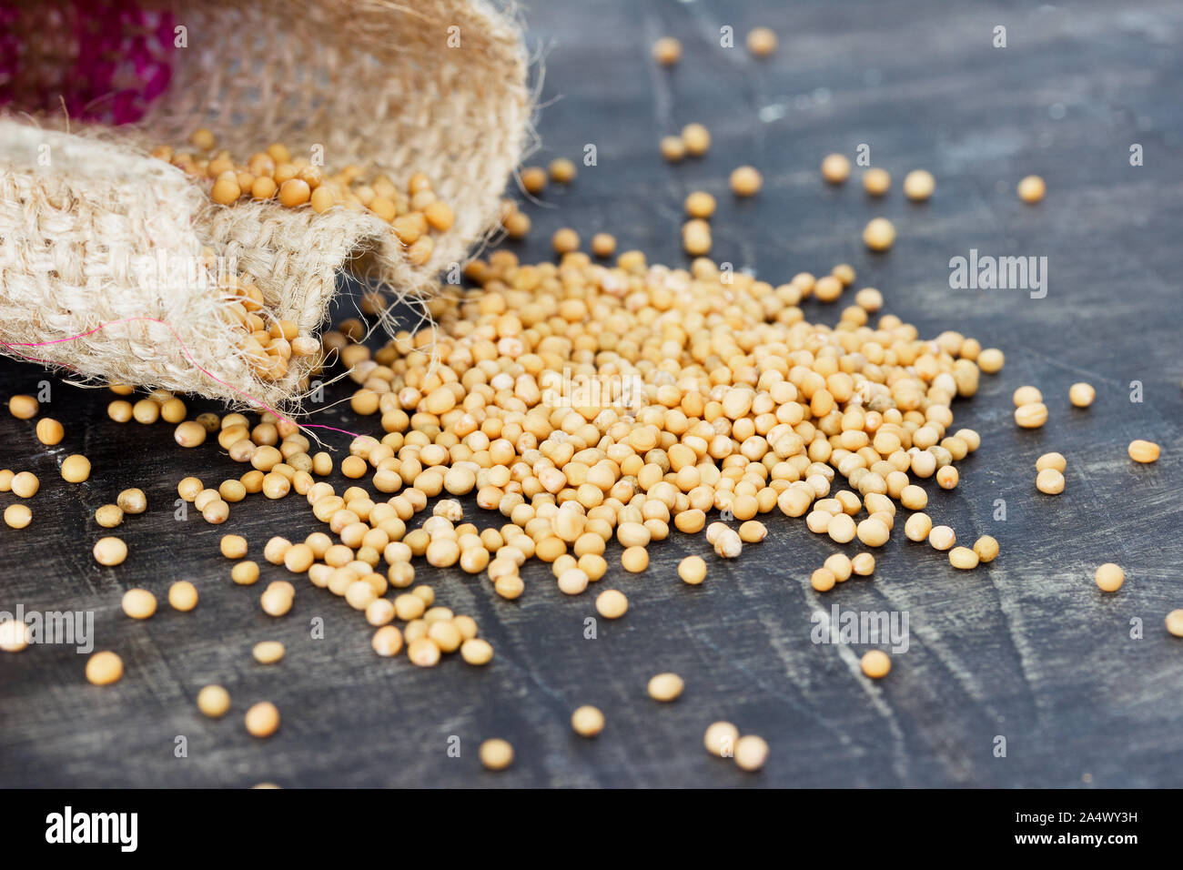 Spilled from the bag of yellow mustard seeds Stock Photo