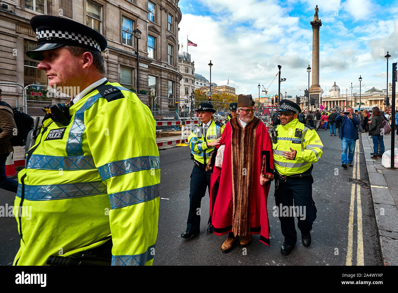 London, U.K. - Oct 16, 2019: Woodbridge mayor and Green Party member Eamonn O'Nolan, dressed in civic robes, is led away by Police after being arrested for blocking a road in Trafalgar Square. Stock Photo