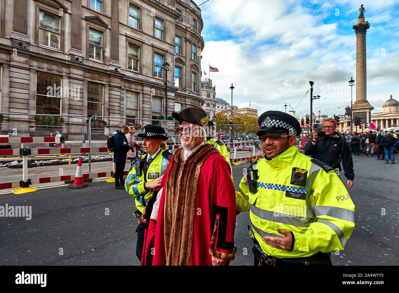 London, U.K. - Oct 16, 2019: Woodbridge mayor and Green Party member Eamonn O'Nolan, dressed in civic robes, is led away by Police after being arrested for blocking a road in Trafalgar Square. Stock Photo