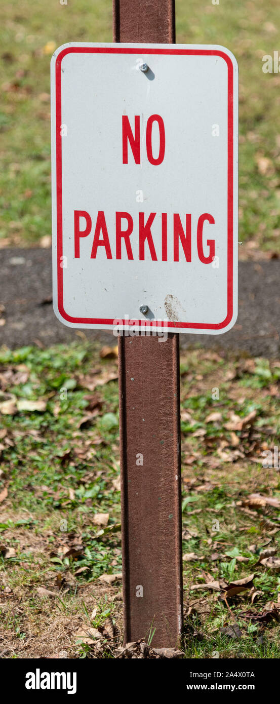 No Parking Sign on Metal Post - Red Writing on White Background. Stock Photo