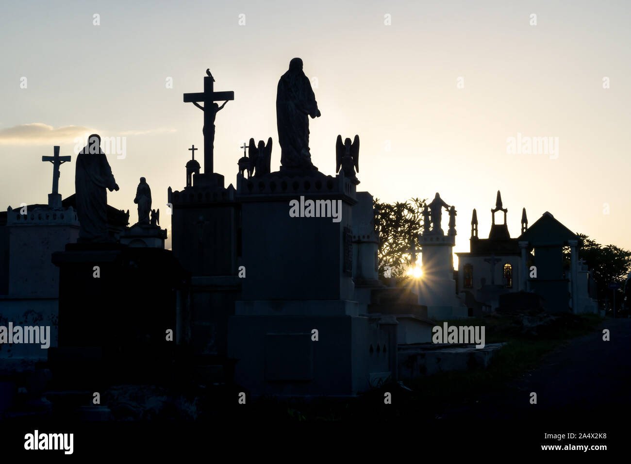 Sunset at cemetery with backlight and silhouettes of the tombs with drosses and Maria statues,Cementerio General, Merida, Mexico Stock Photo